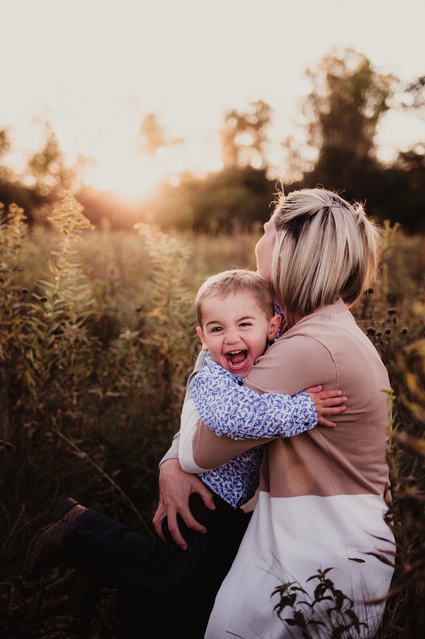 Candid laughing moment between adult and child during outdoor photoshoot.