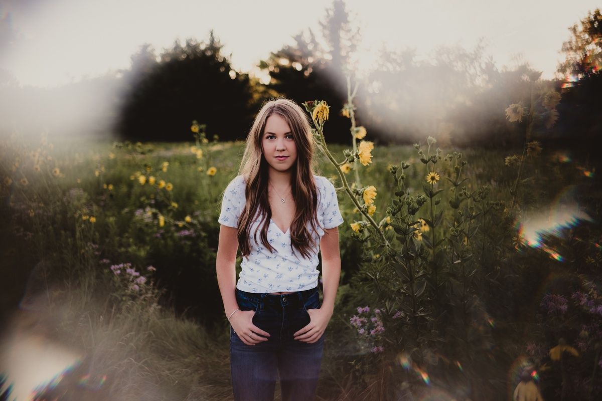 Atmospheric portrait in a meadow with ethereal lighting and wildflowers.