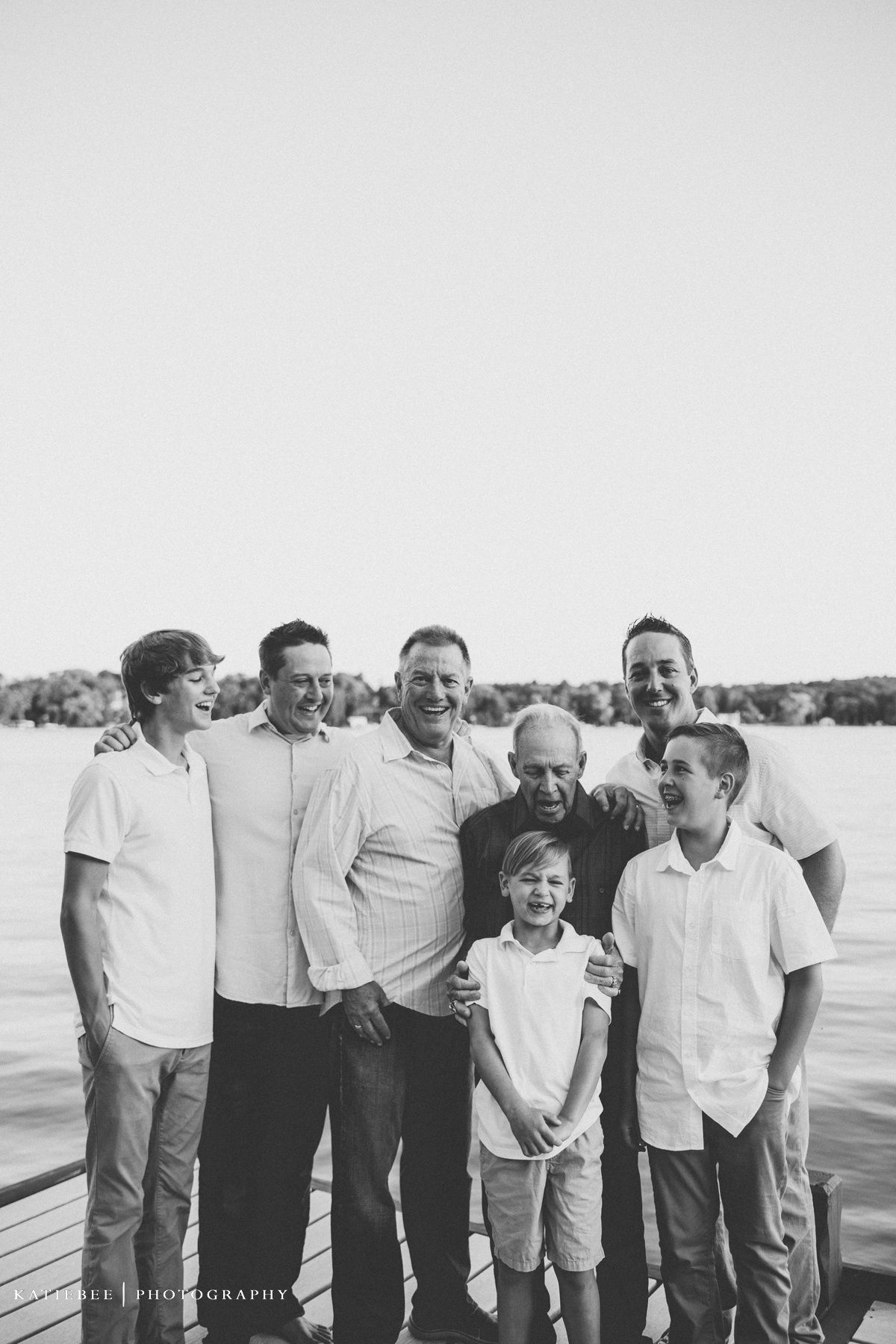 Black and white portrait of male family members standing together by waterfront.