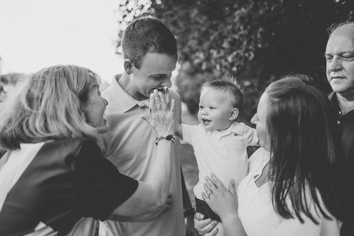 A candid black and white family gathering showing playful interaction in an outdoor setting.