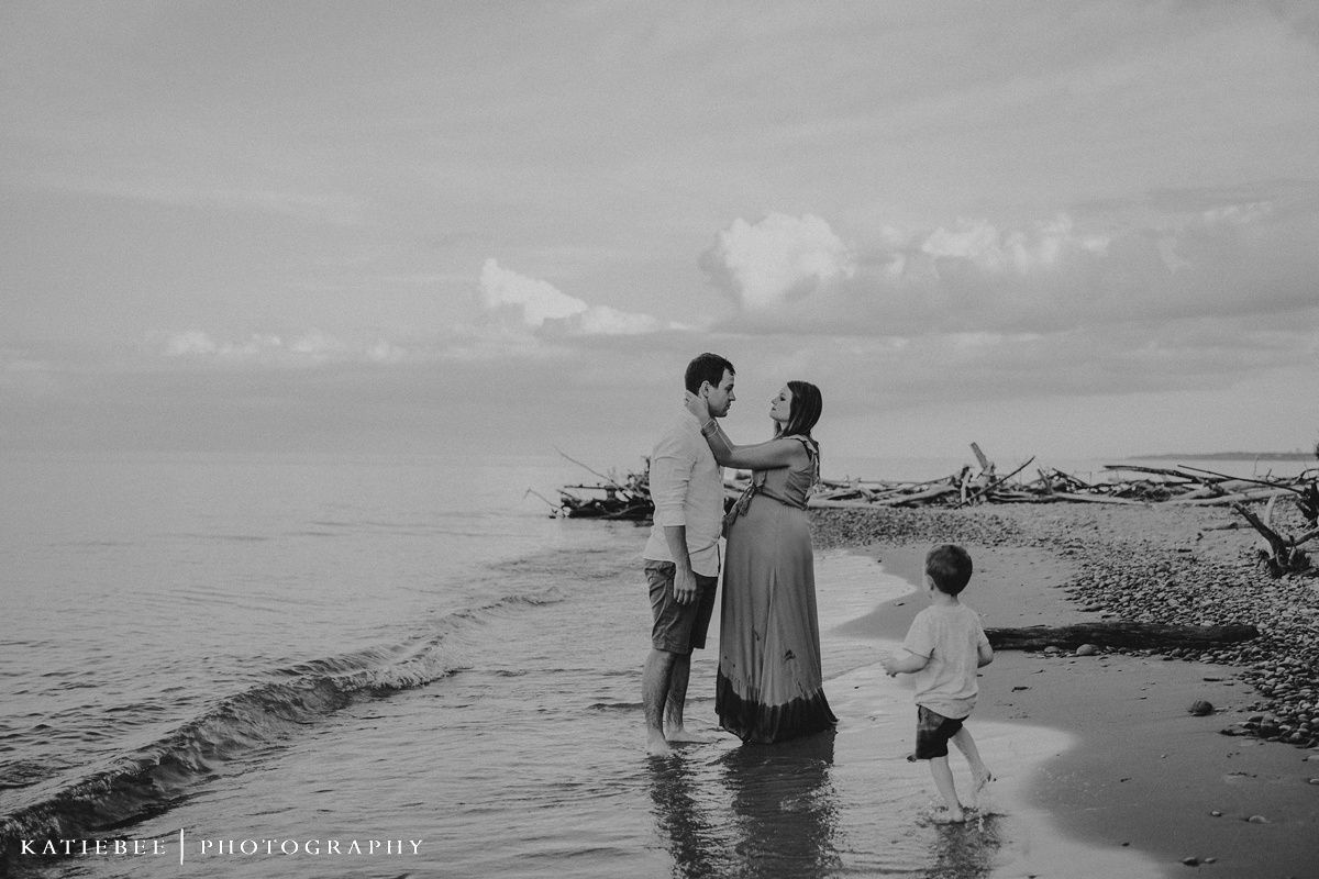 A black and white beach scene shows a family enjoying a moment together by the water.