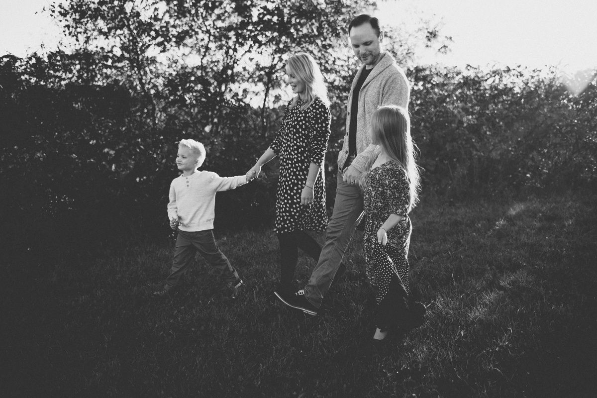 A black and white photo of a family walking together outdoors in nature.