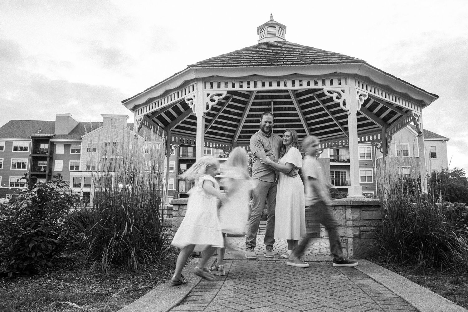 A series of black and white wedding photos showing romantic moments at a gazebo and garden venue.
