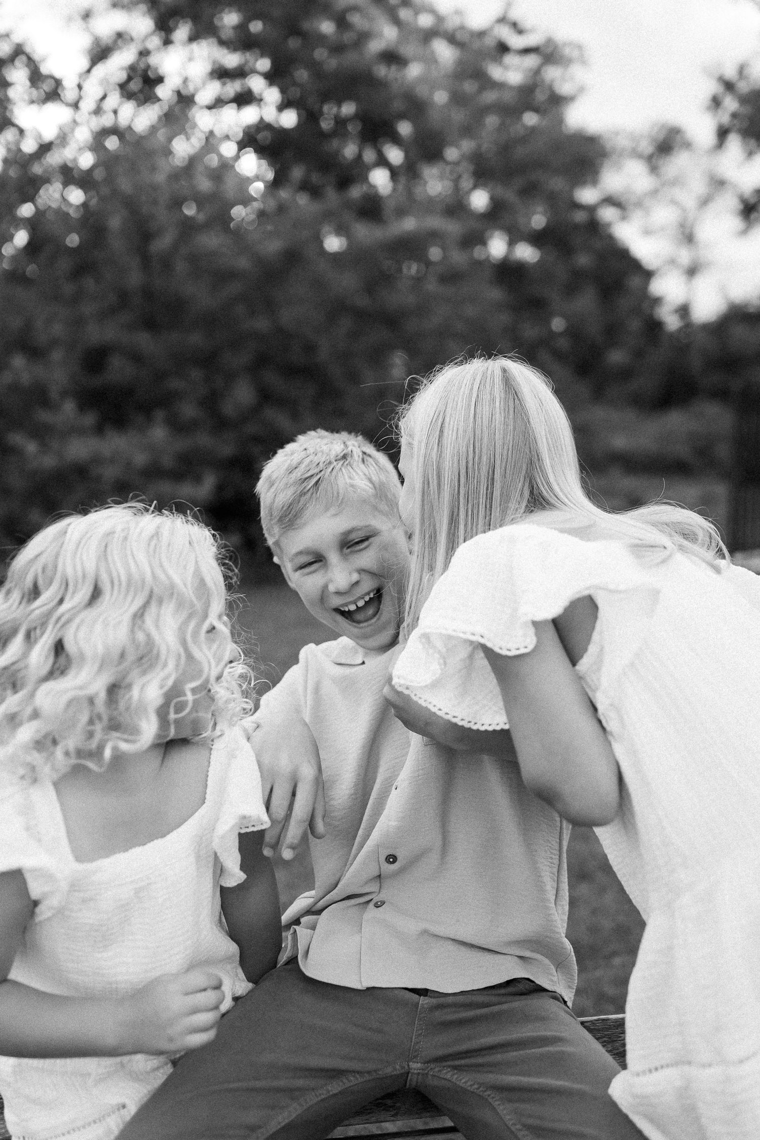 A black and white panoramic photo shows a group of people in white clothing laughing together outdoors.