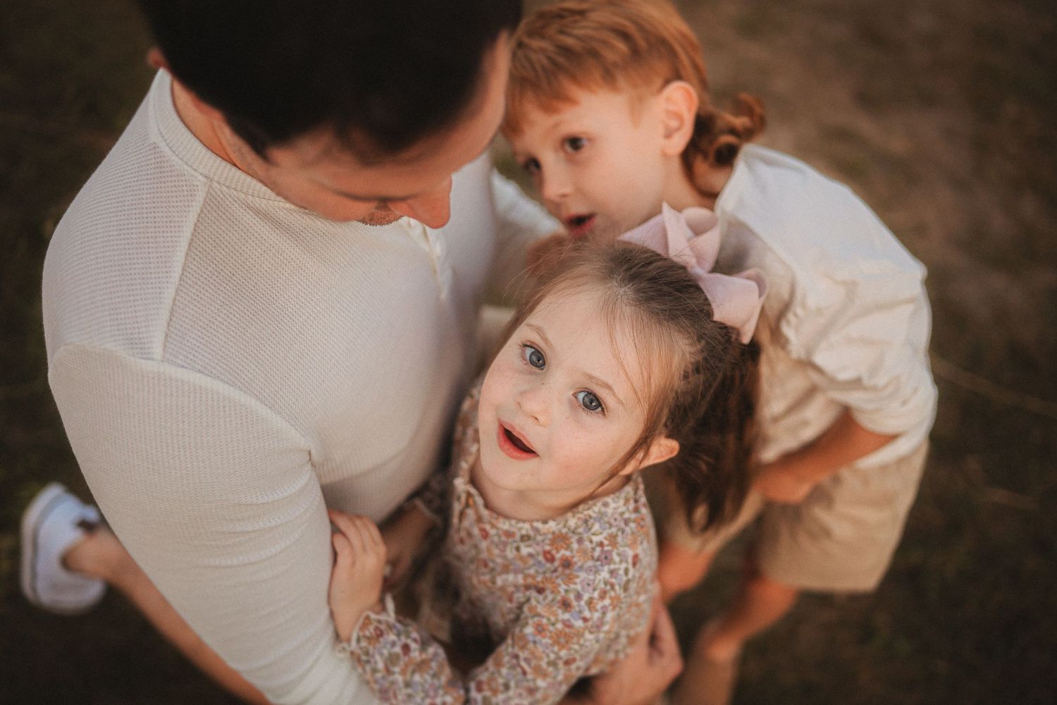Overhead closeup portrait of parent with children looking up and smiling.