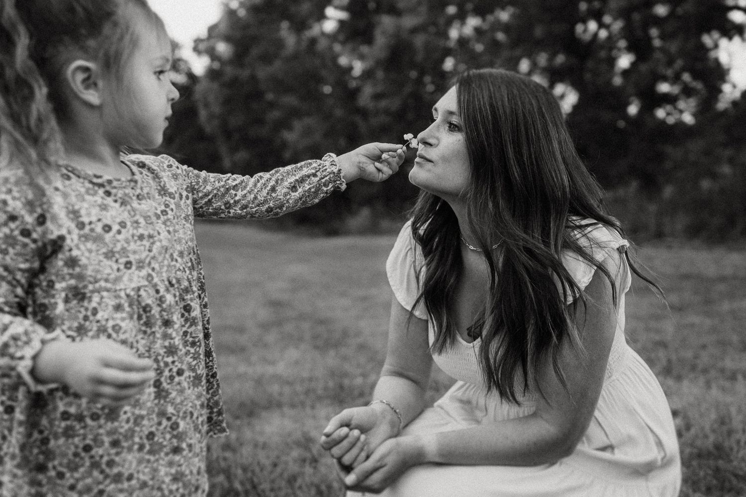 Sweet moment of play between two people in a grassy field in black and white.