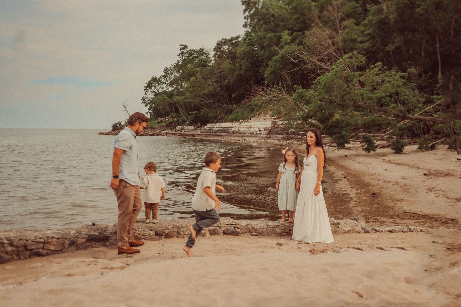Family enjoying a playful moment together on a scenic beach with cliffs and ocean in the background.