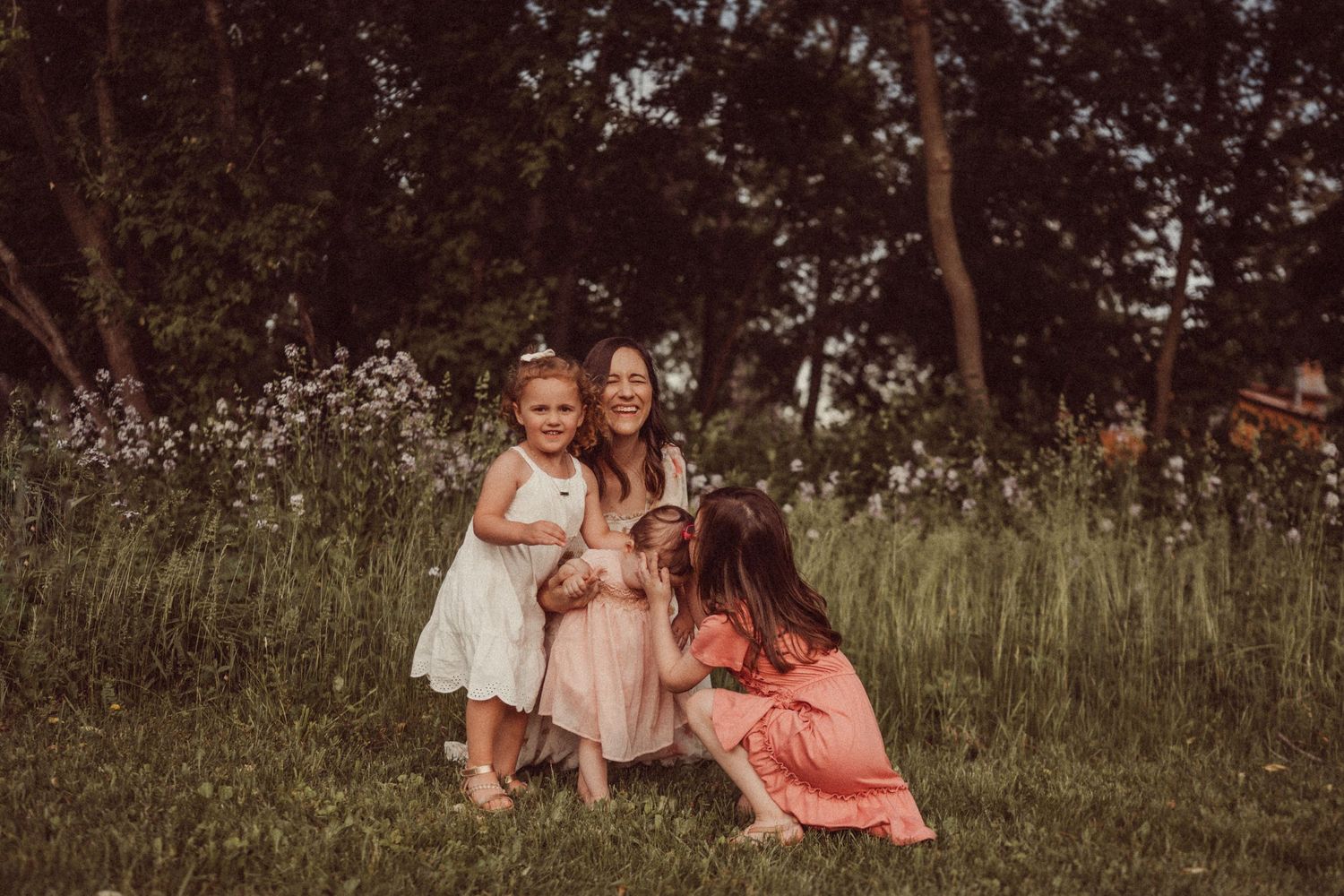 Three people share a sweet moment together in a field of white wildflowers.