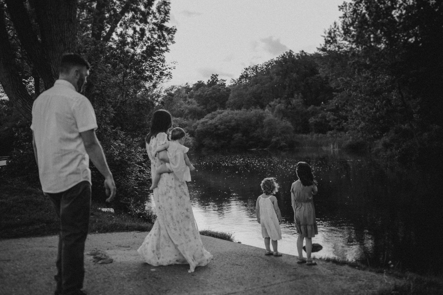 A peaceful evening walk along a serene waterfront path with trees in the background.