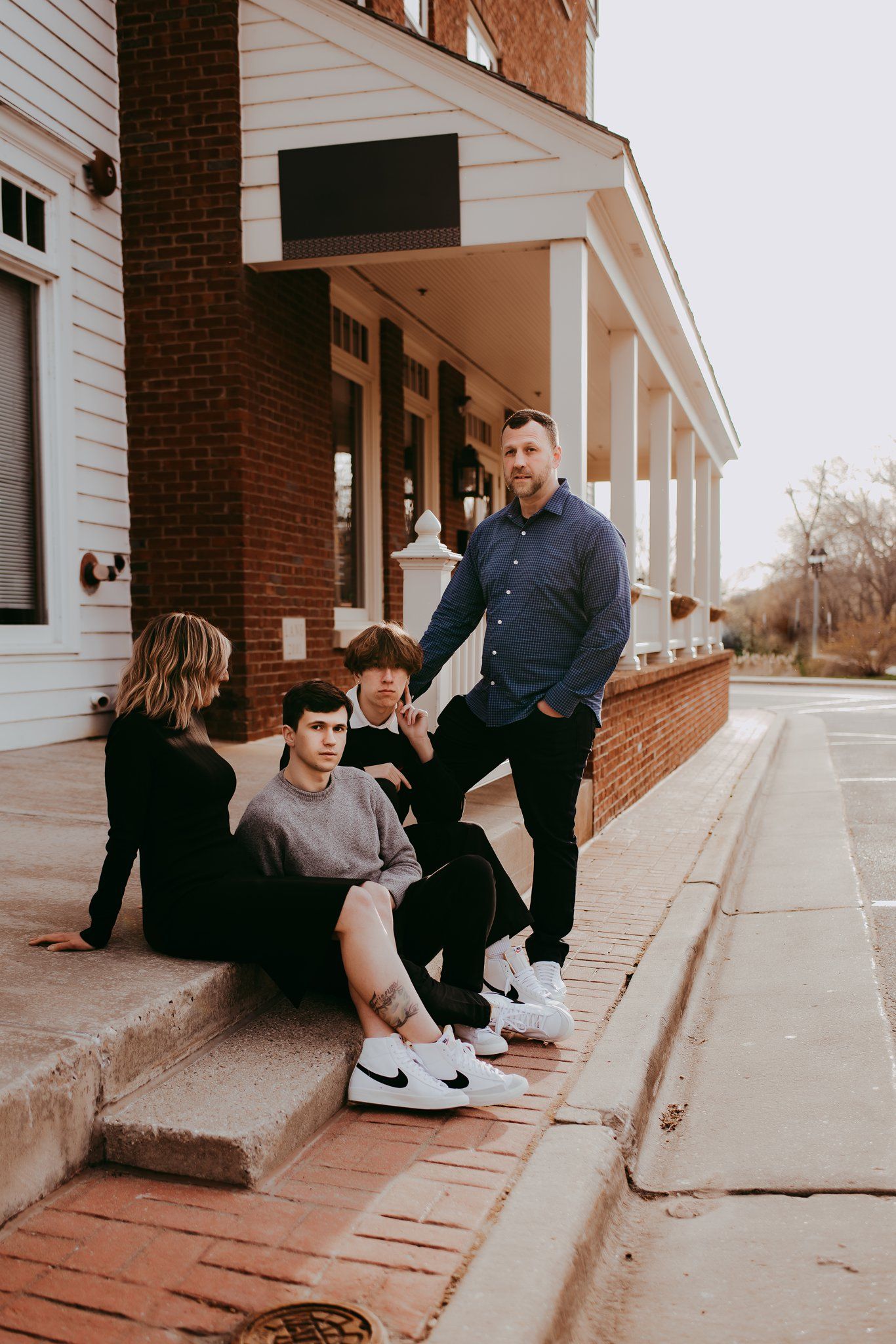 Group sitting casually on brick steps of a building wearing matching white sneakers.