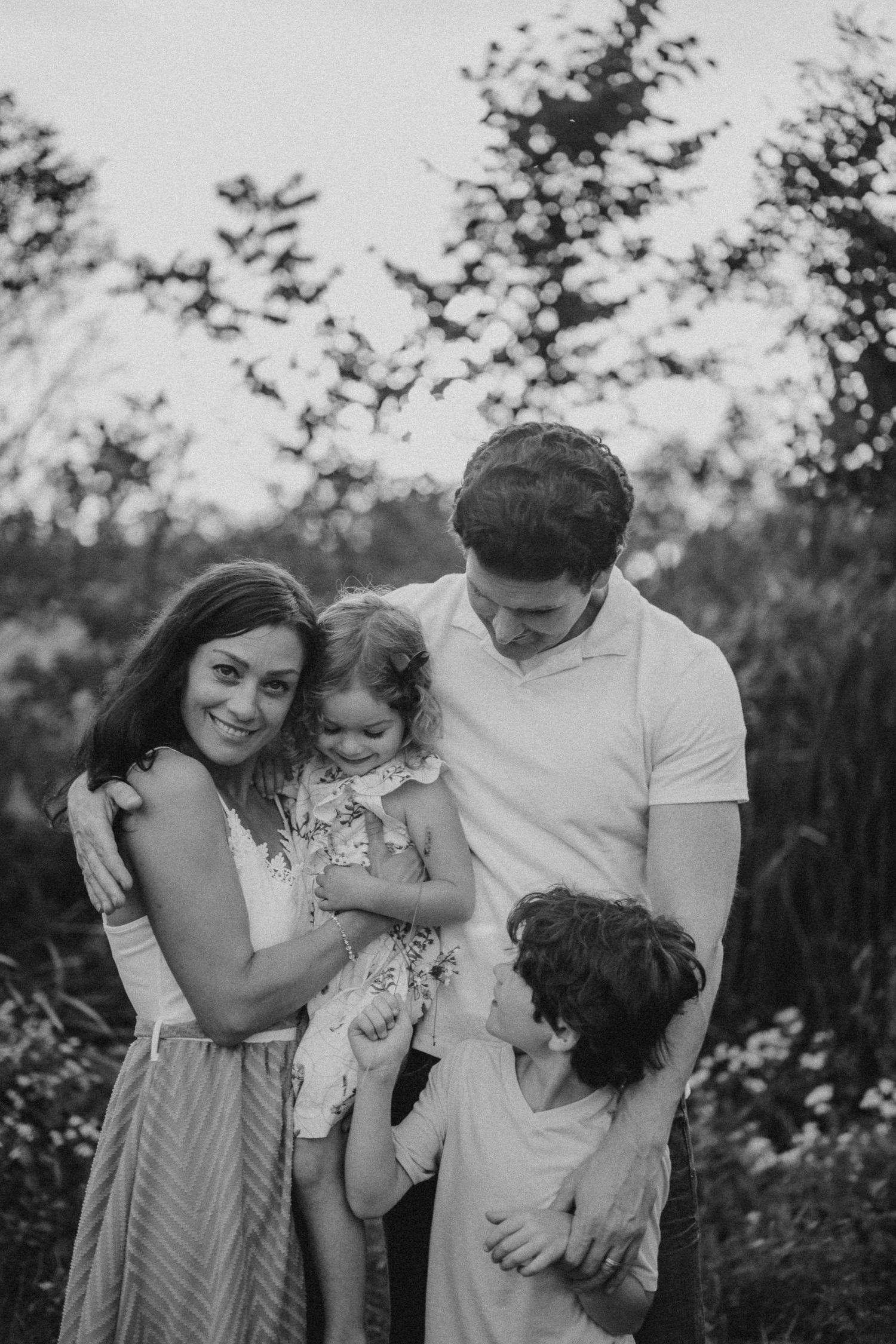A black and white portrait of a family gathered close together outdoors.