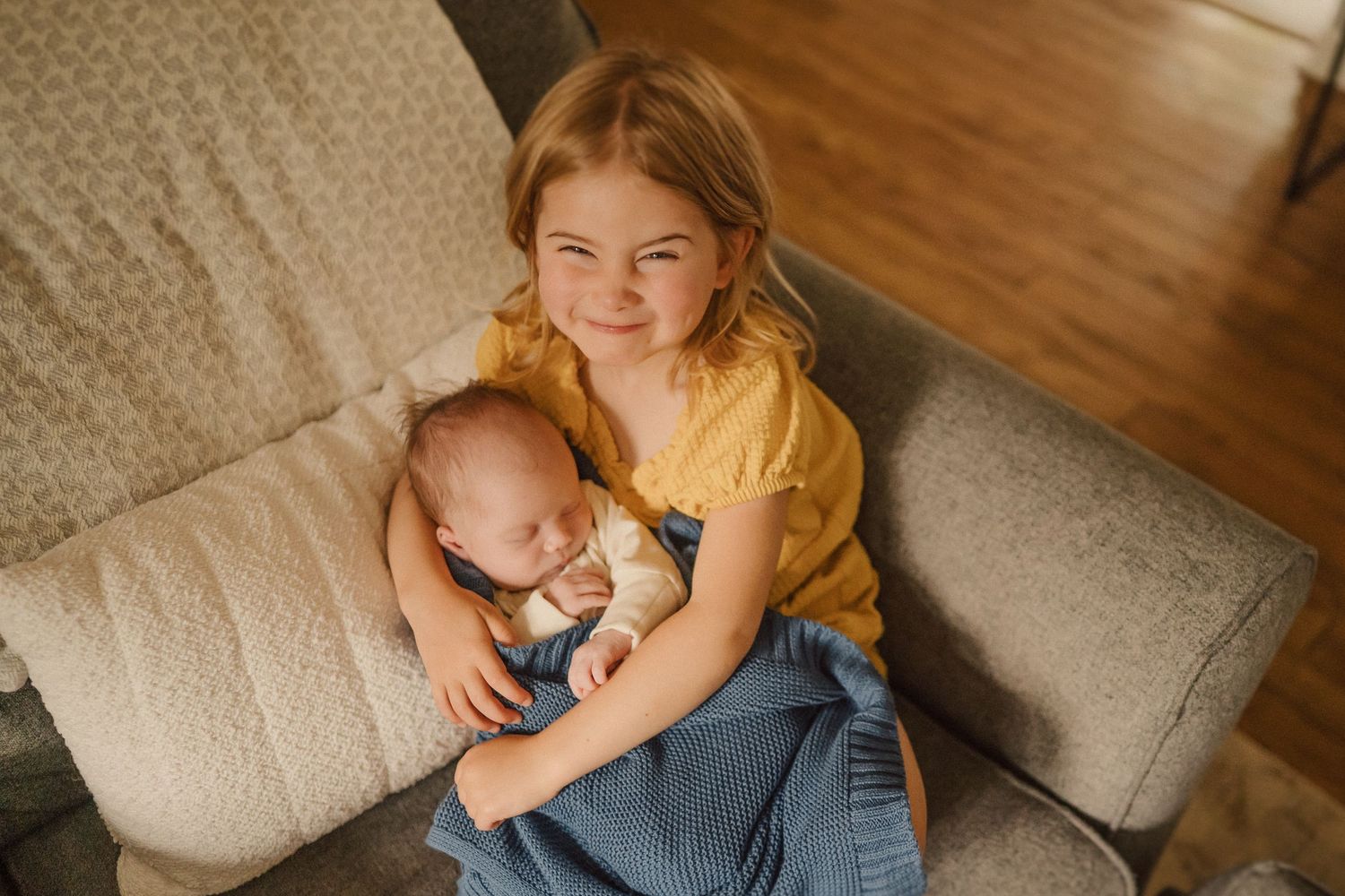 A heartwarming moment showing gentle interaction with an infant on a cream-colored couch.