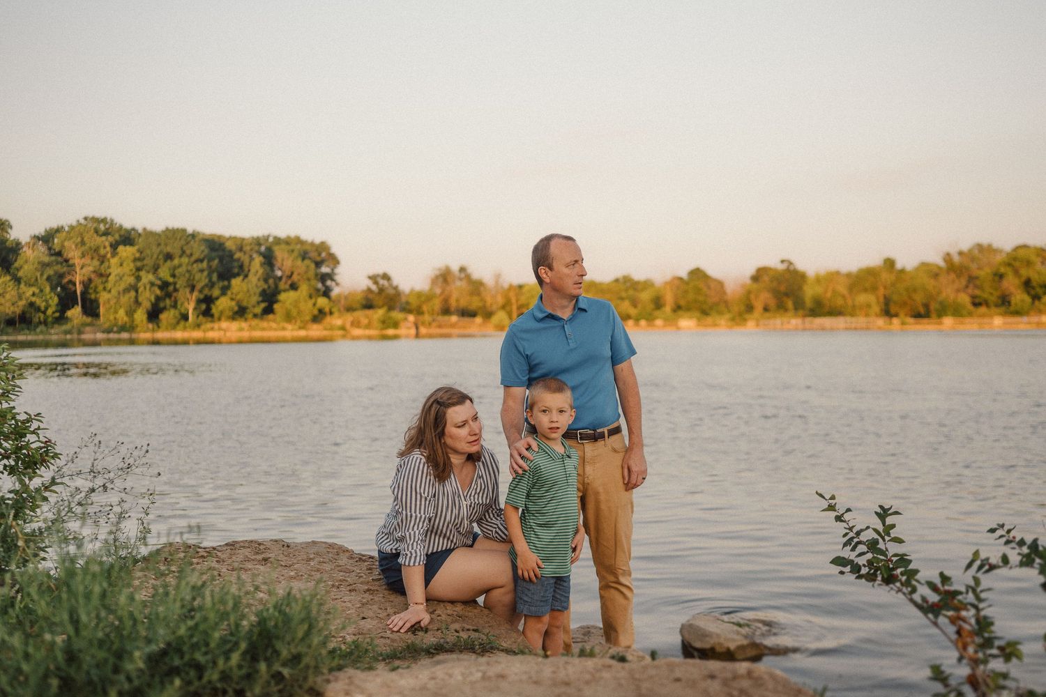 Family enjoys peaceful moments together by a serene lake during sunset.