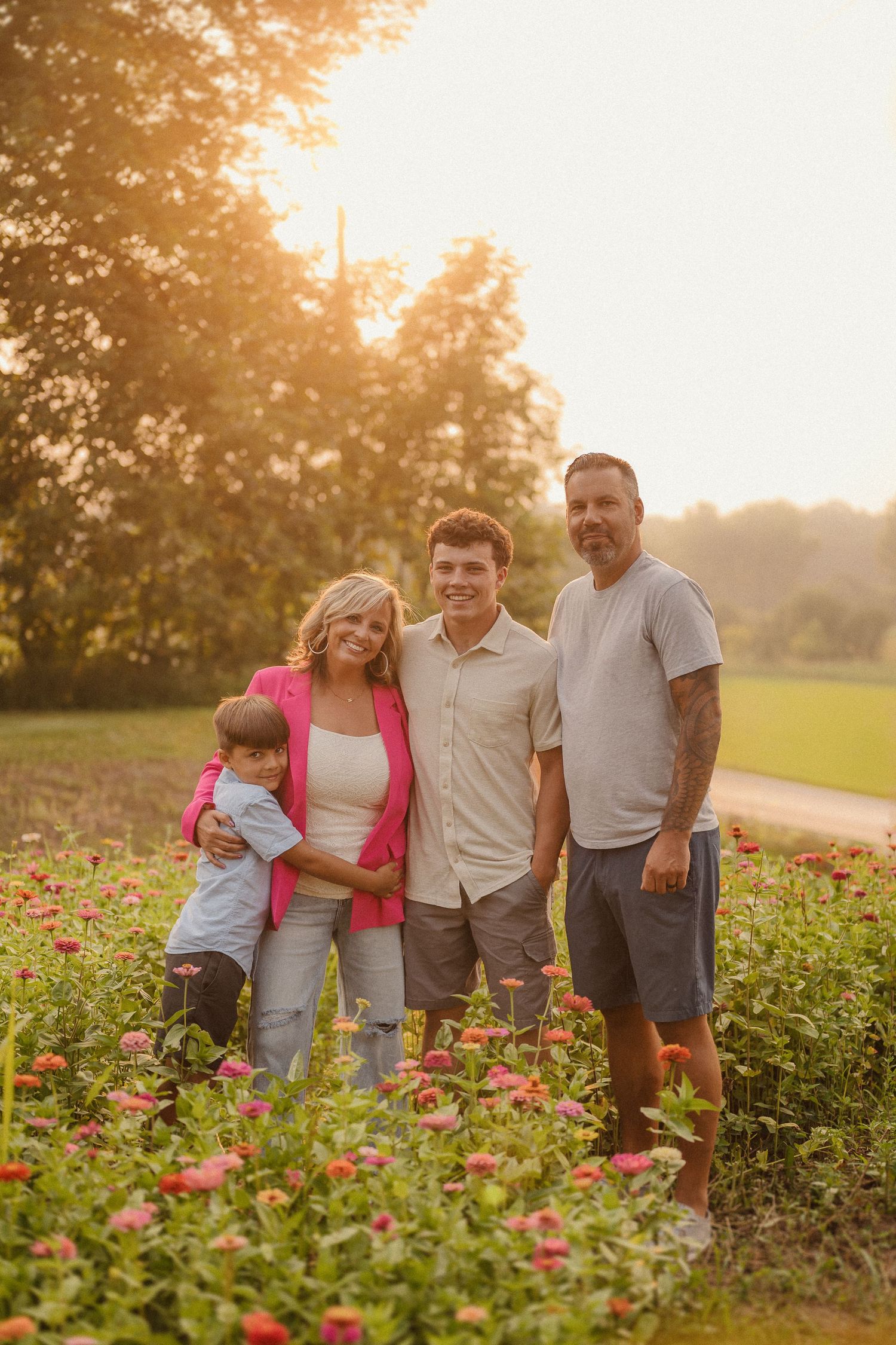 Family poses together in a vibrant meadow at golden hour with red flowers in bloom.