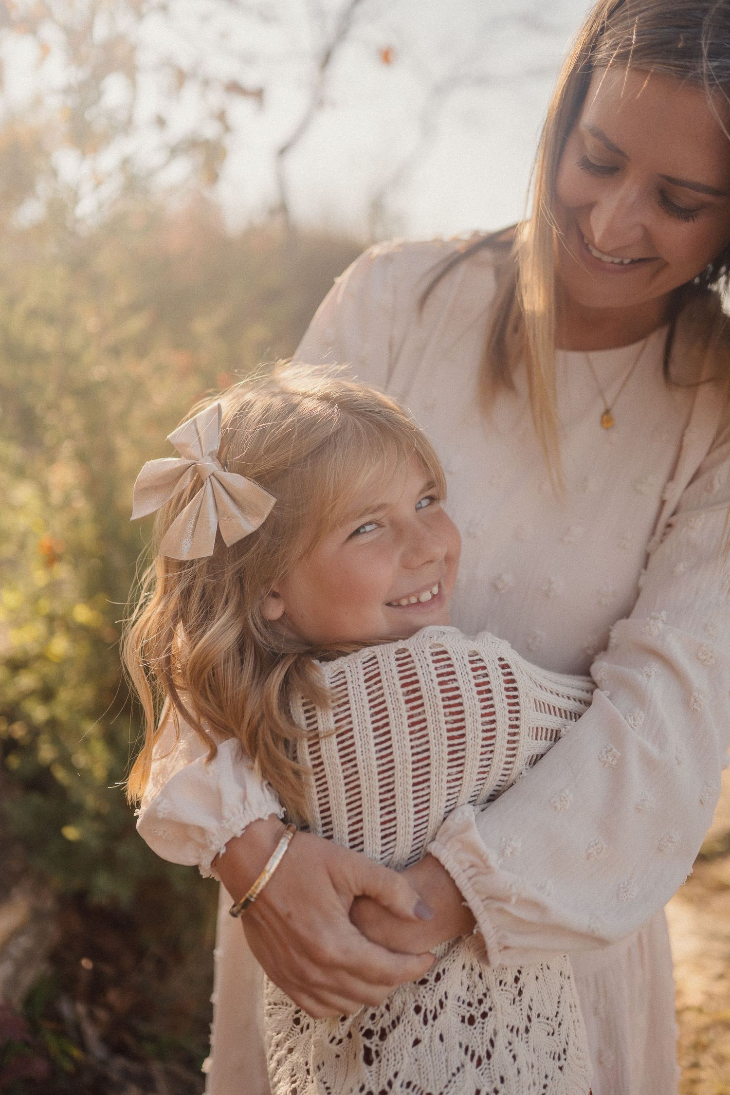 A tender moment captured between parent and child in soft natural lighting with autumn trees in background.