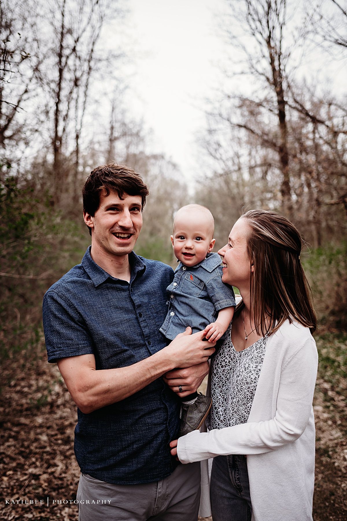 Candid family moment showing shared laughter on wooded path.