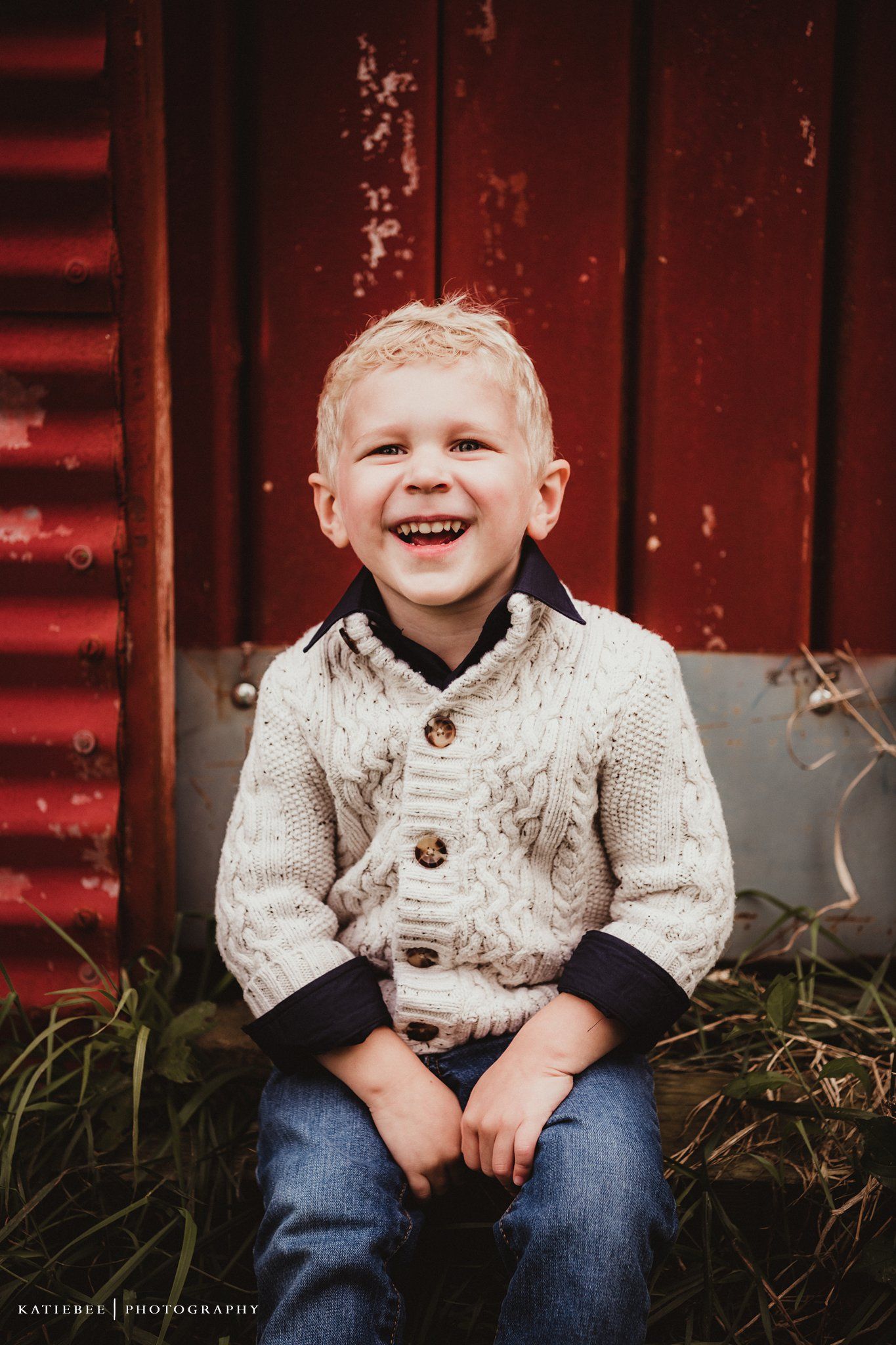 A bright smile captured against weathered red barn siding.