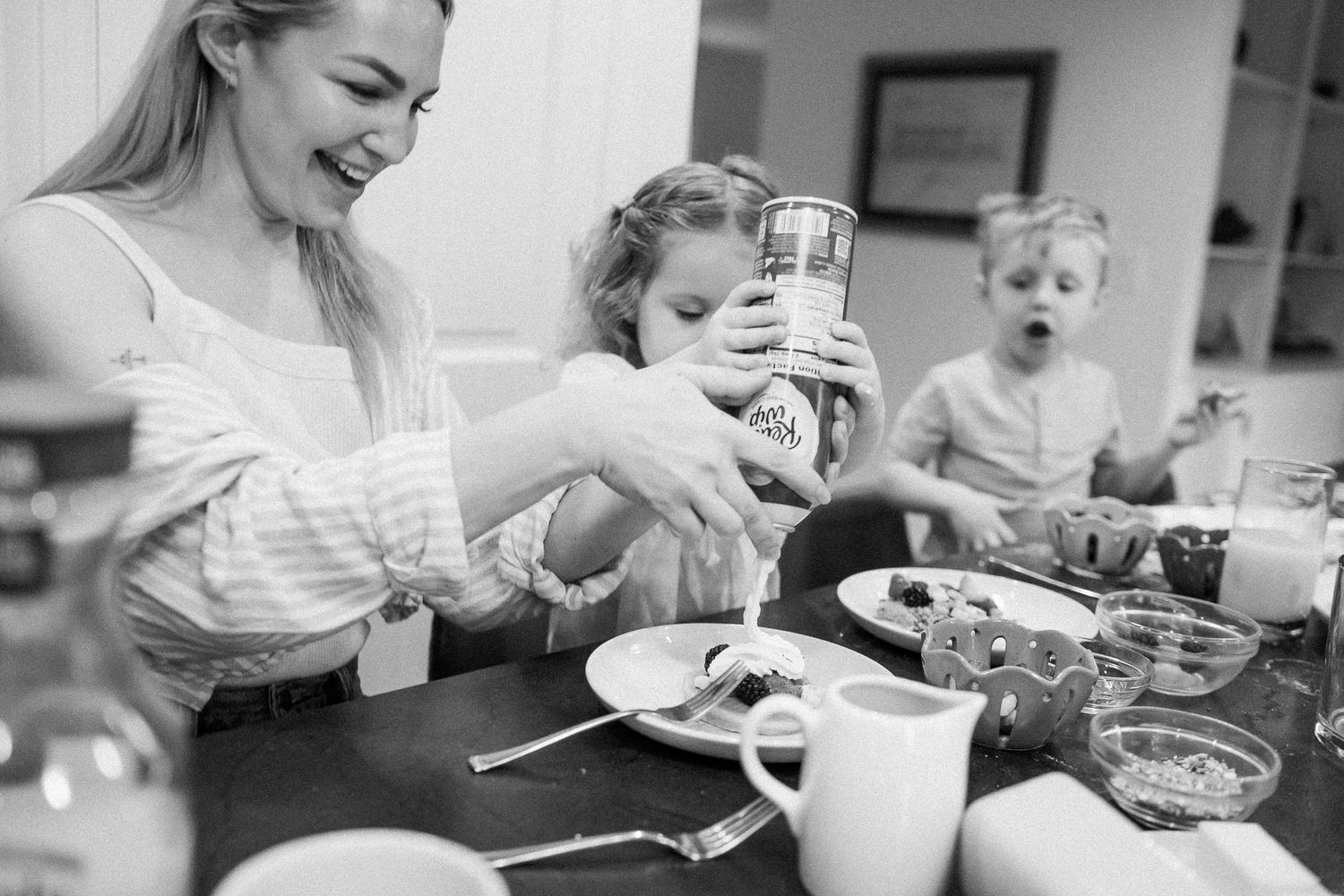 Black and white photo of a mother and two children enjoying a pancake breakfast at the kitchen table.