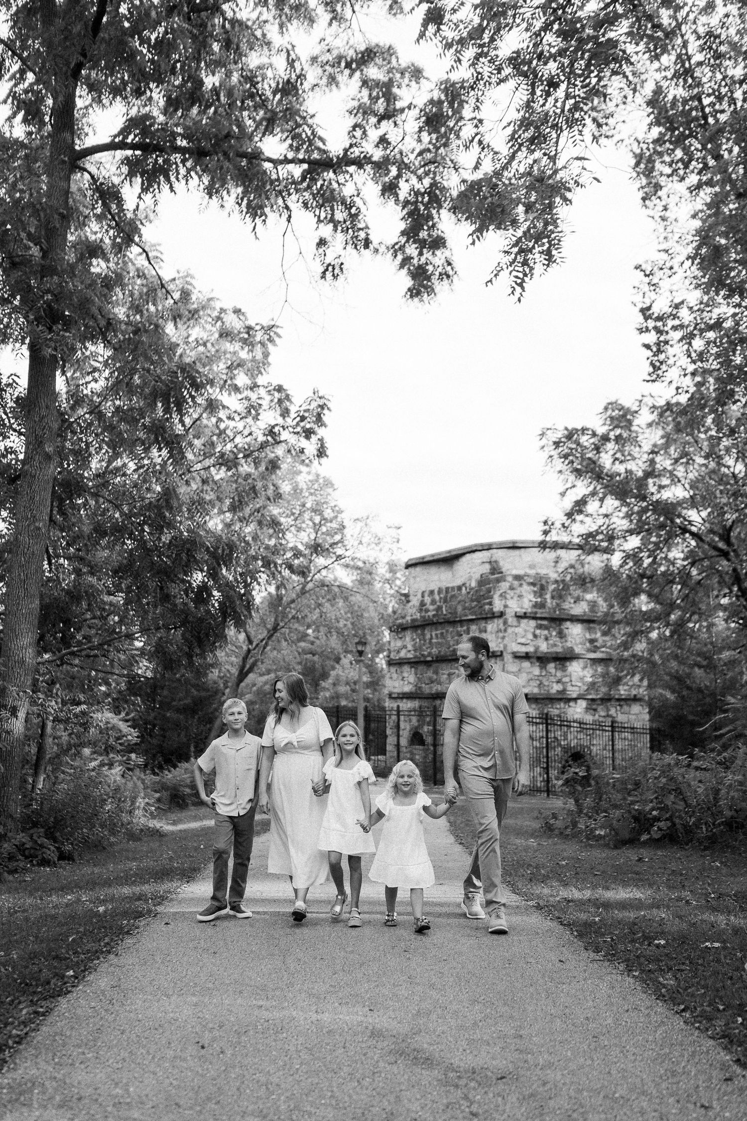 Black and white photo of a group walking together on a tree-lined path.