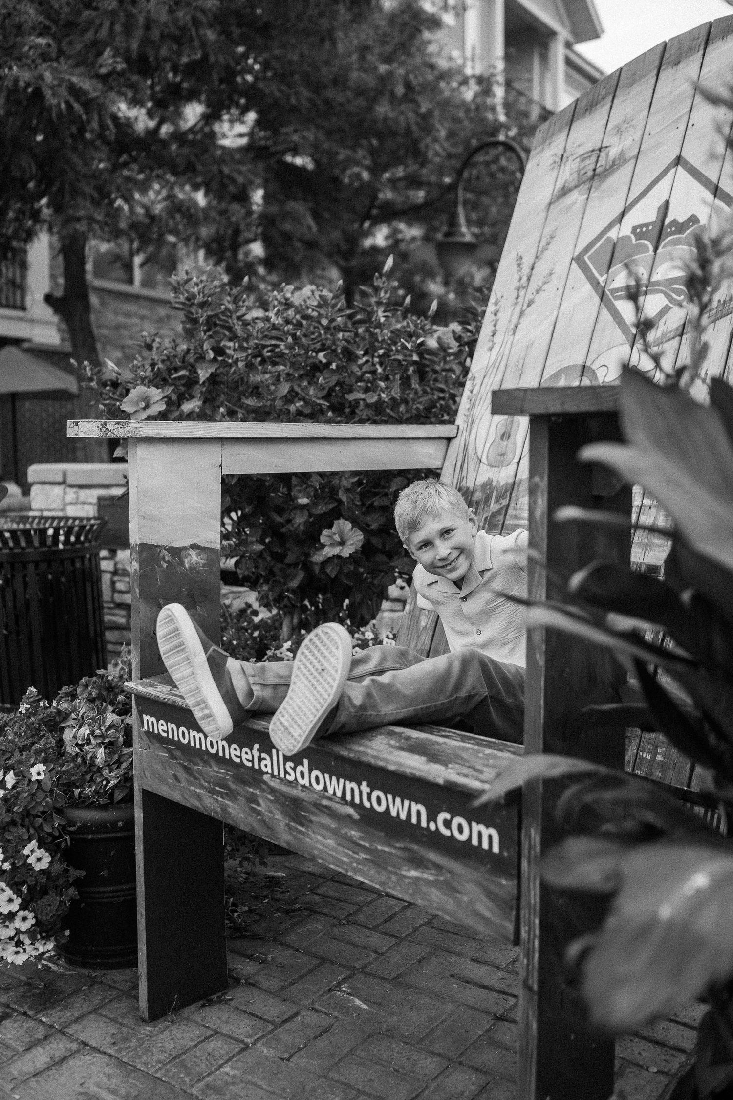 Black and white photos show a sequence of playful poses on a bench in an urban setting.
