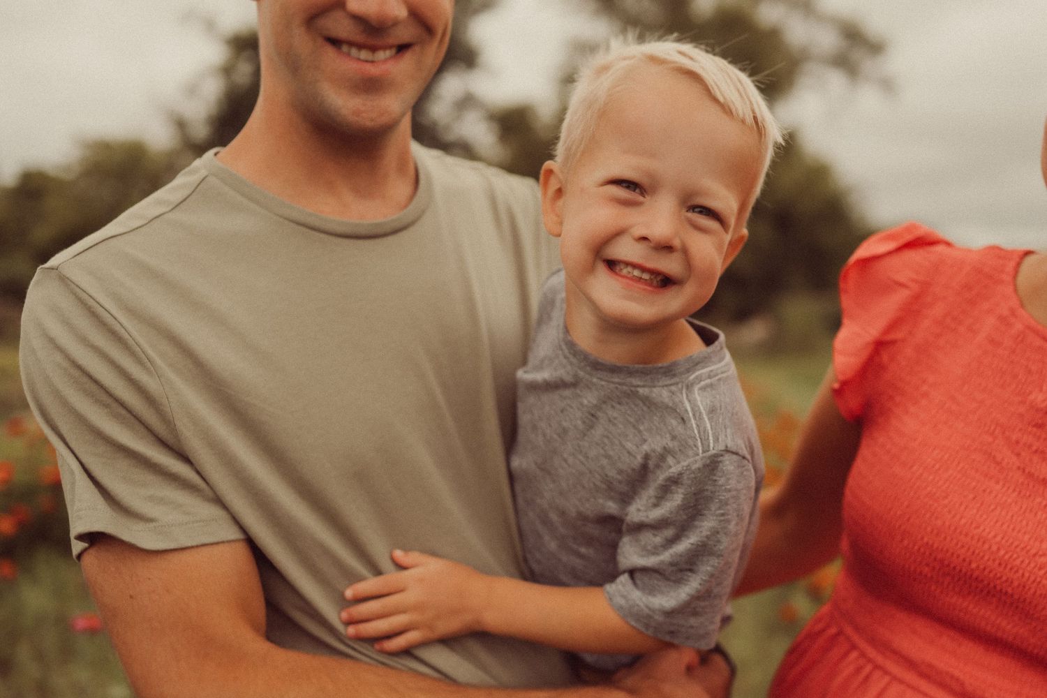 A heartwarming family moment captured against a background of flowers on a cloudy day.