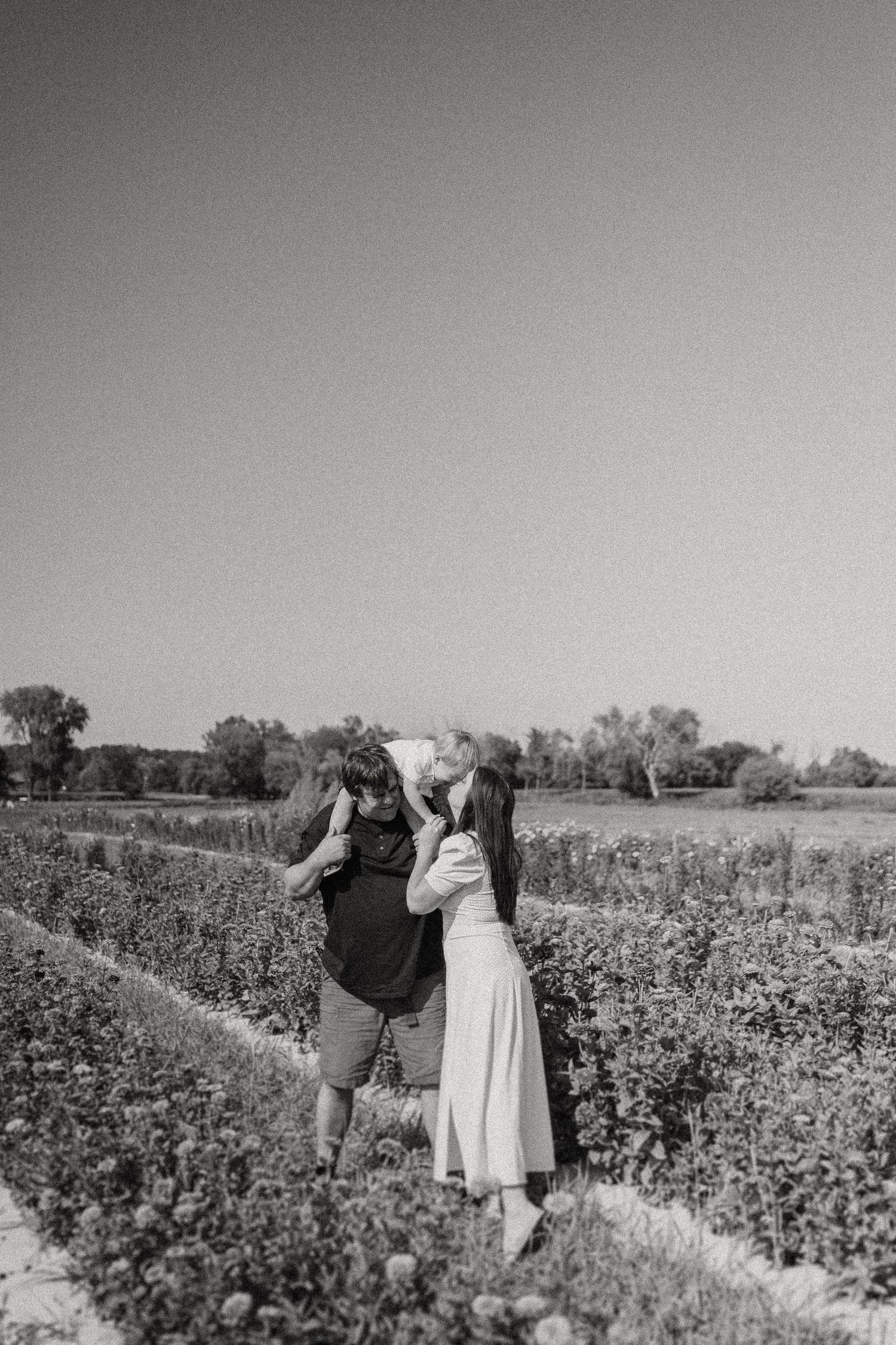 Two figures explore a flowering field in black and white photography.
