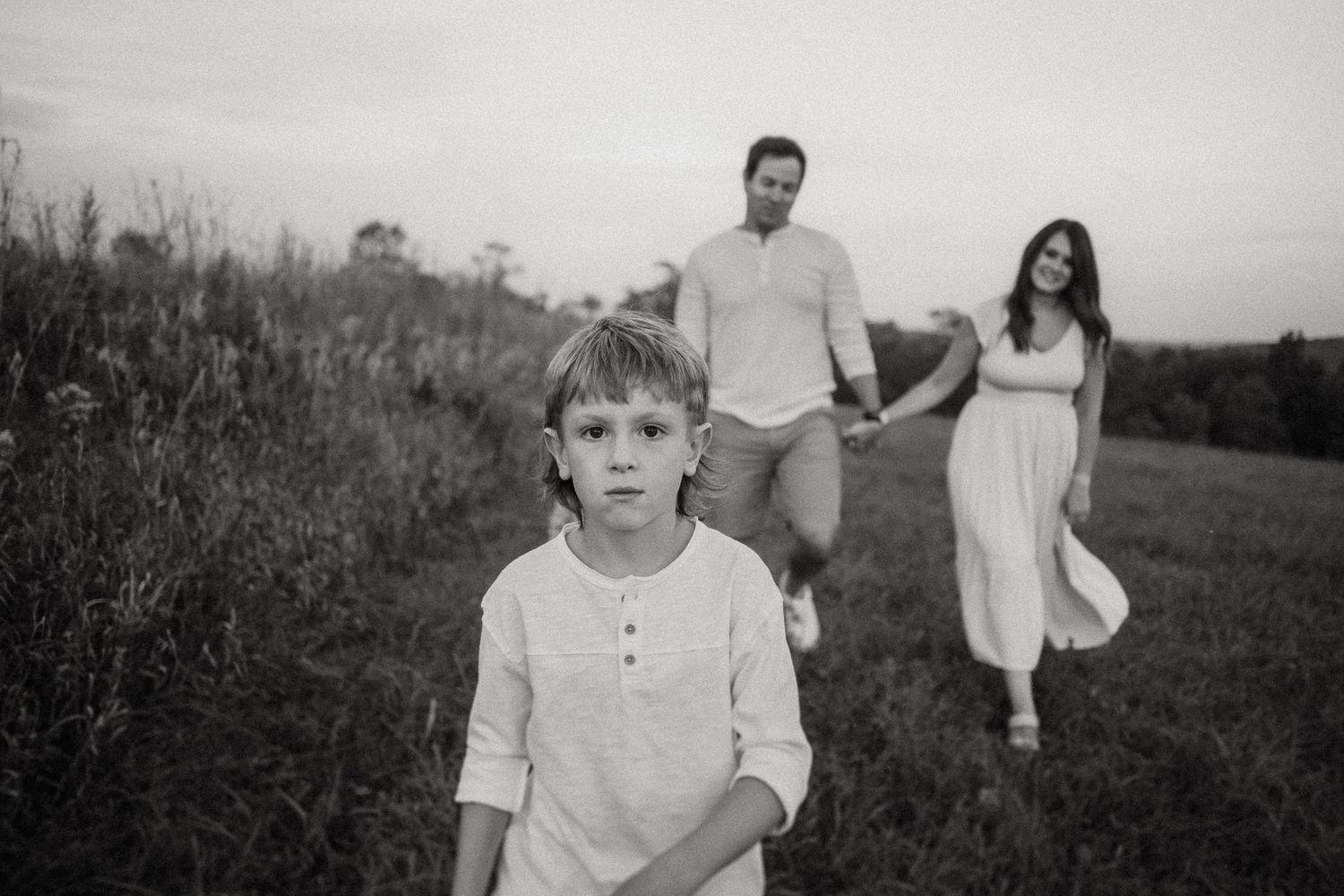 Candid black and white family portrait in a rustic field setting.