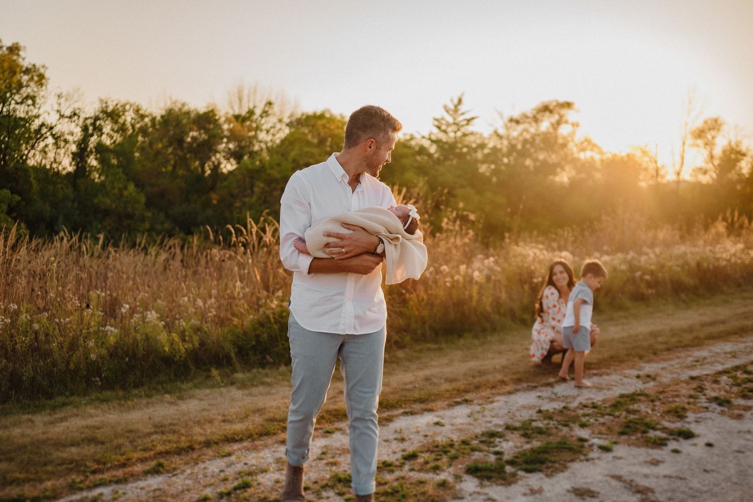Sunset family photoshoot with warm golden light in natural field setting.