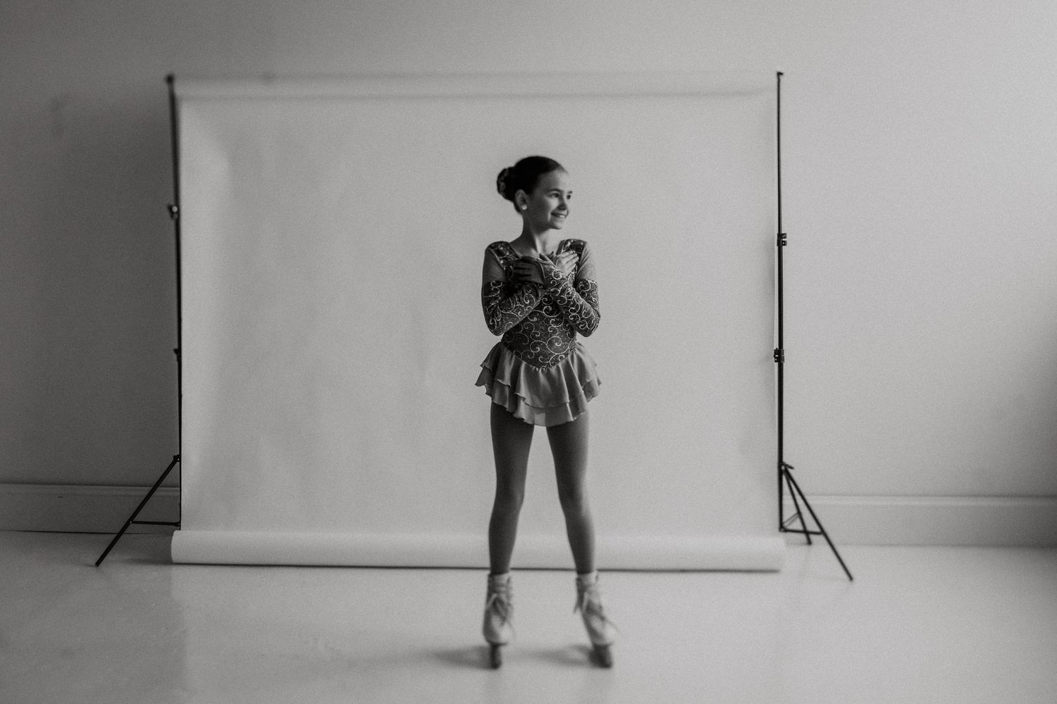 Silhouette of figure skater en pointe in costume against white studio backdrop.