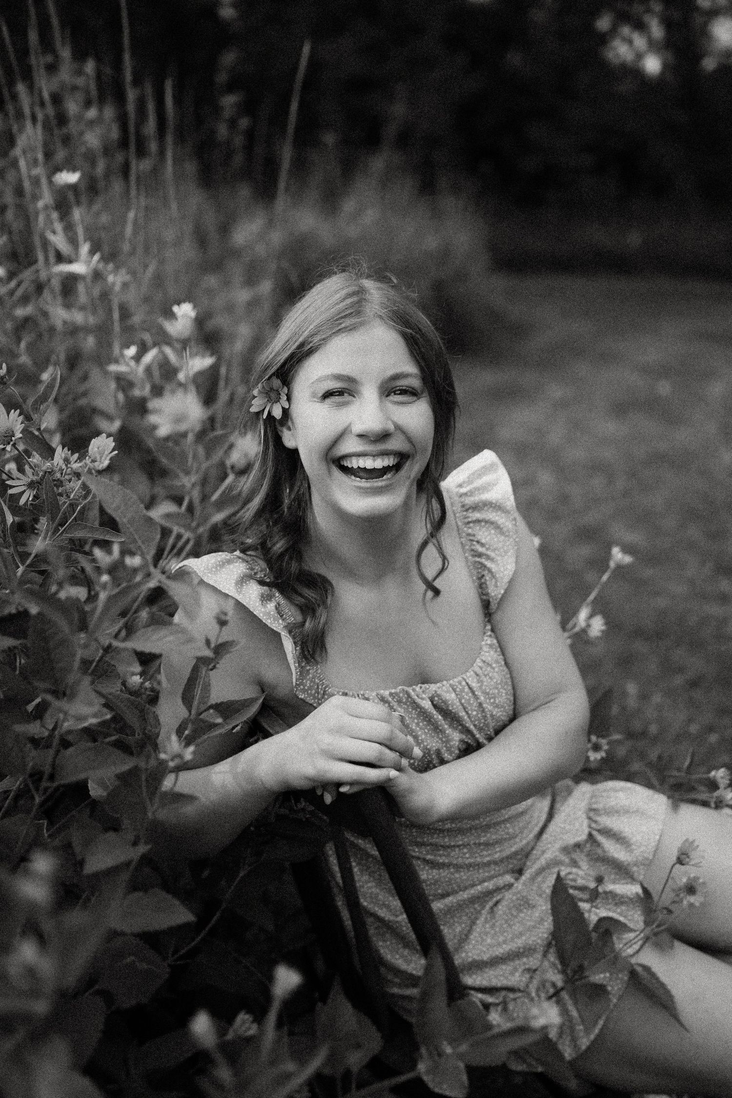 Candid black and white moment captured in a garden with joyful laughter.