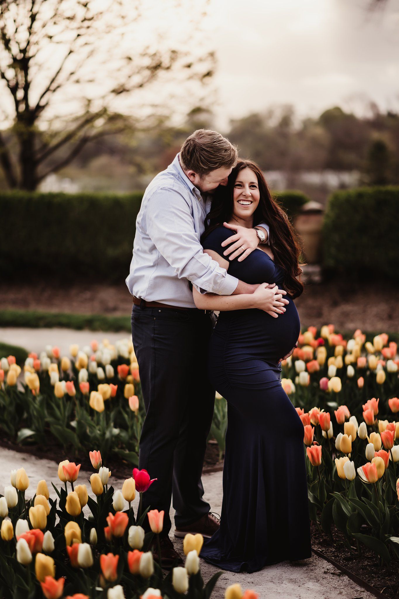 Romantic maternity portrait of couple embracing among blooming spring tulips.