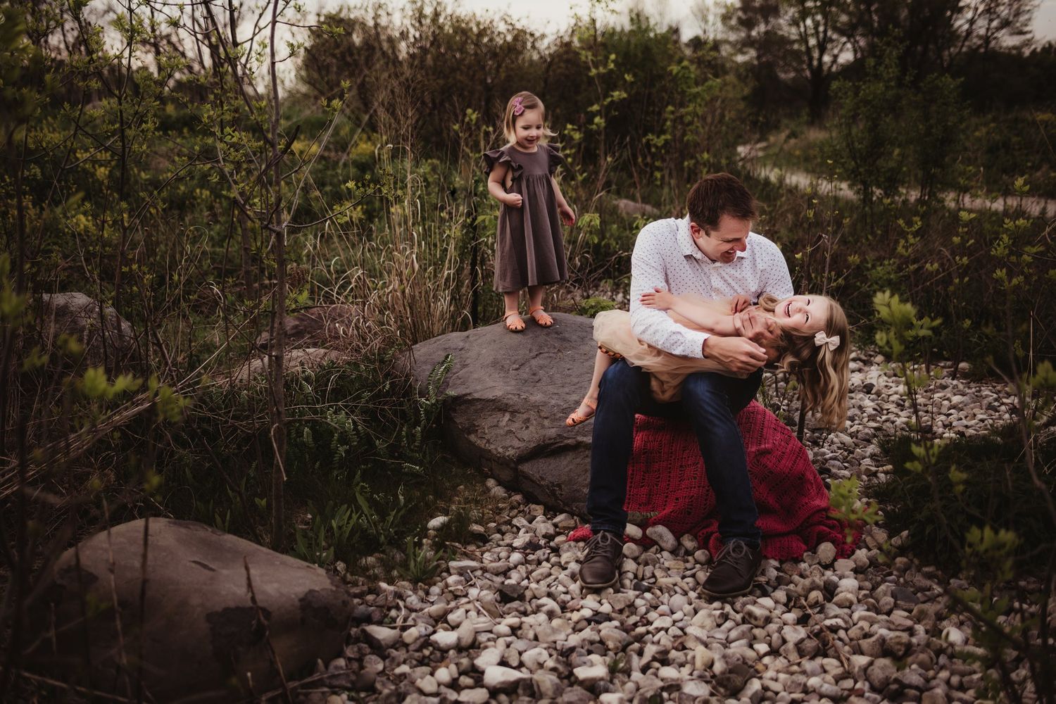A touching family moment captured on a rocky terrain with scattered white petals.