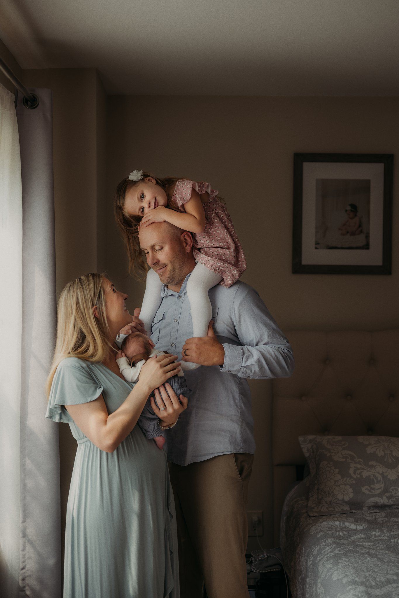 Joyful family portrait with playful poses near a bright window.