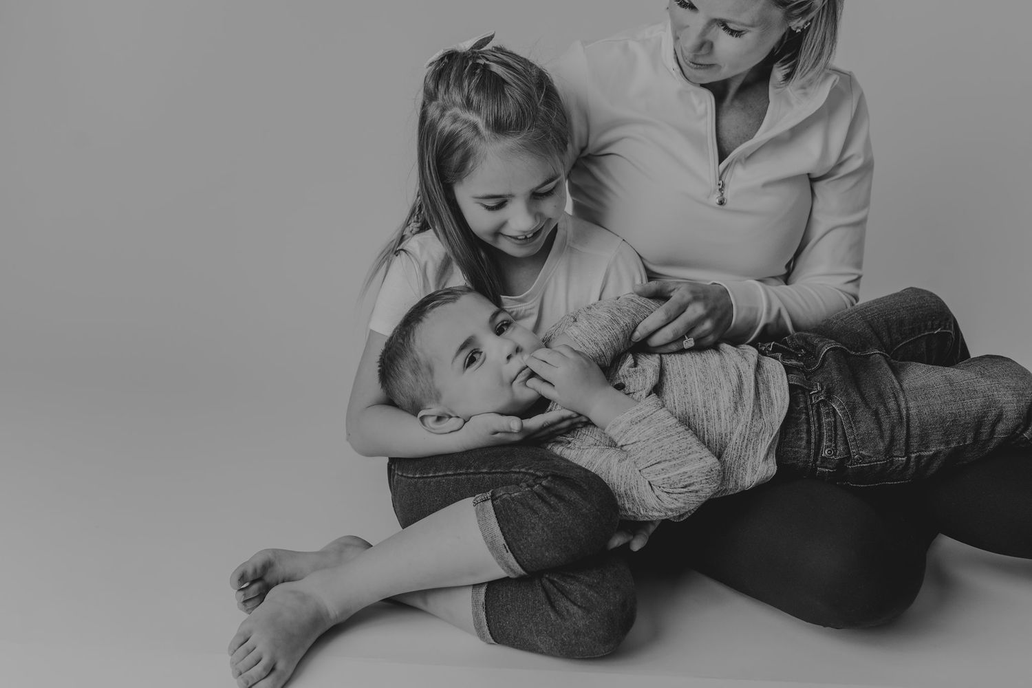 Black and white candid photo capturing joyful family laughter during studio session.