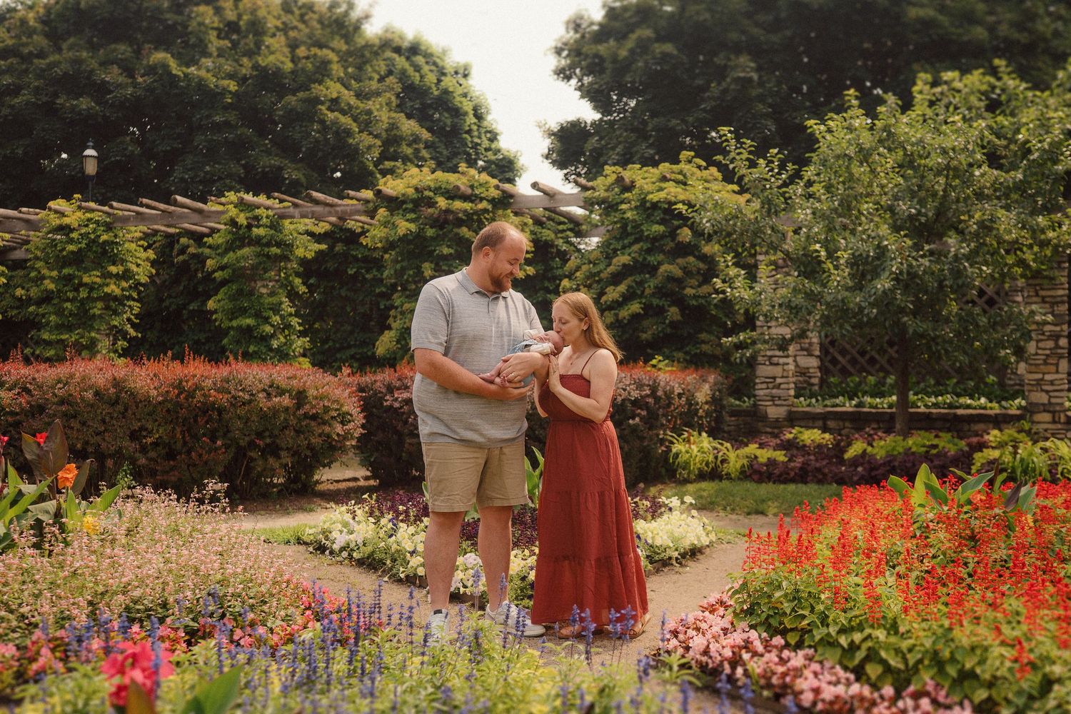 A couple shares a romantic moment together surrounded by vibrant summer flowers in a lush garden setting.