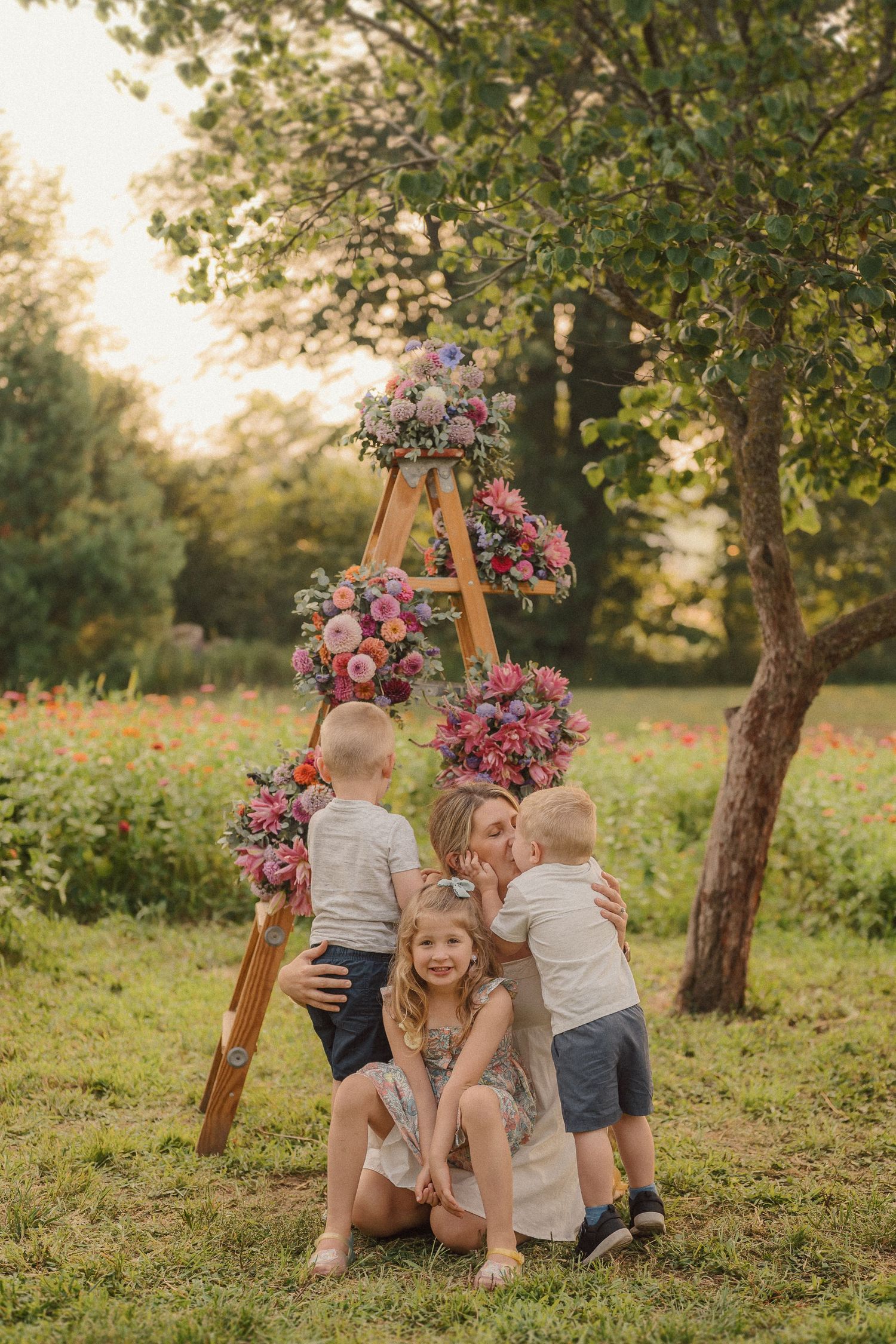 Children playing near a floral arch in a sunny garden setting during a golden hour photoshoot.