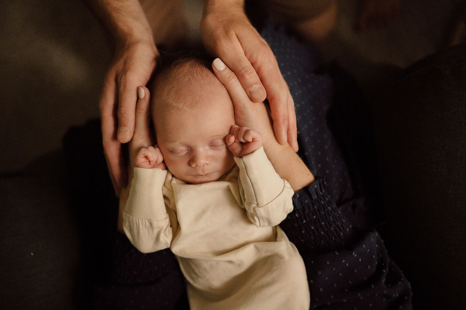 Close-up shots of gentle baby care moments in dark lighting.
