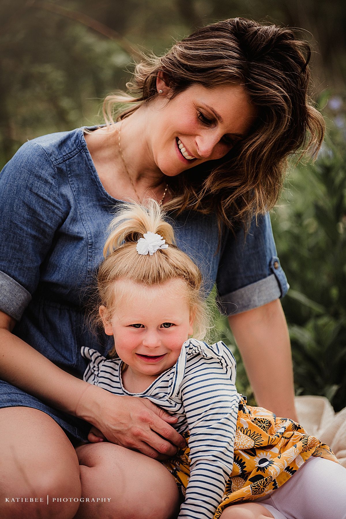 A loving portrait of two people embracing while sitting outdoors in casual denim and stripes.