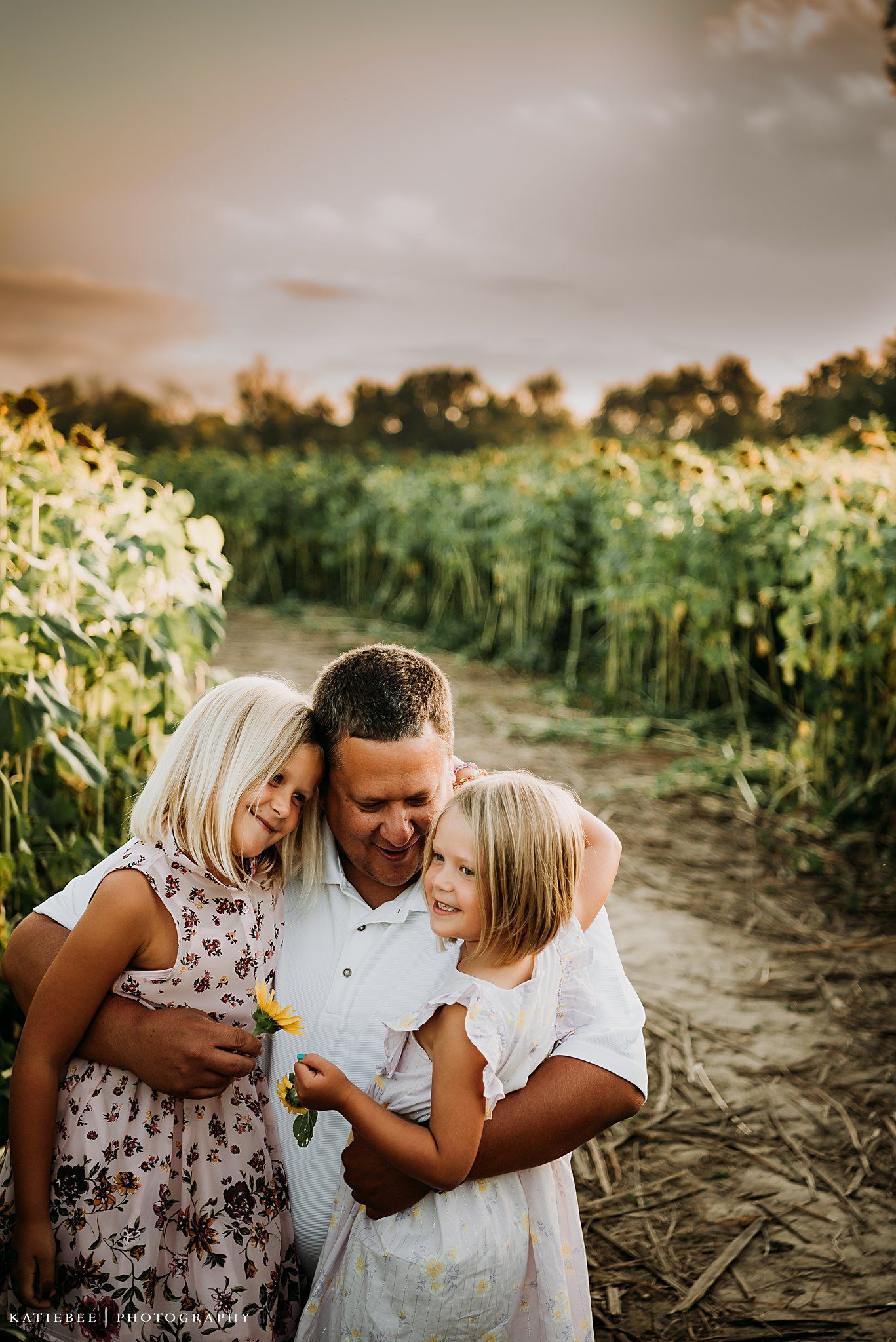 Joyful family embrace captured during sunset in a blooming sunflower field.