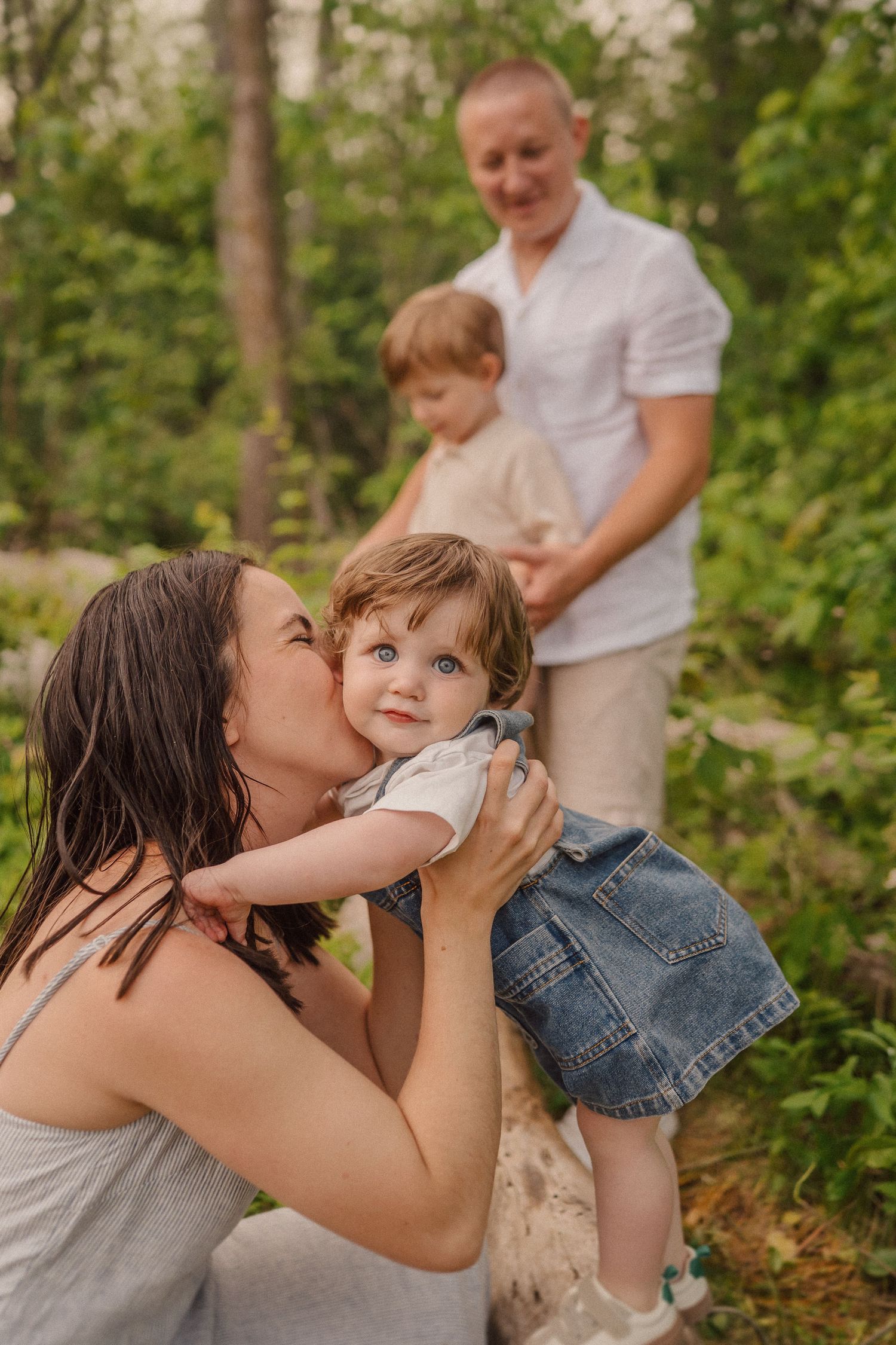 A tender moment captured in a wooded setting with light streaming through the trees.
