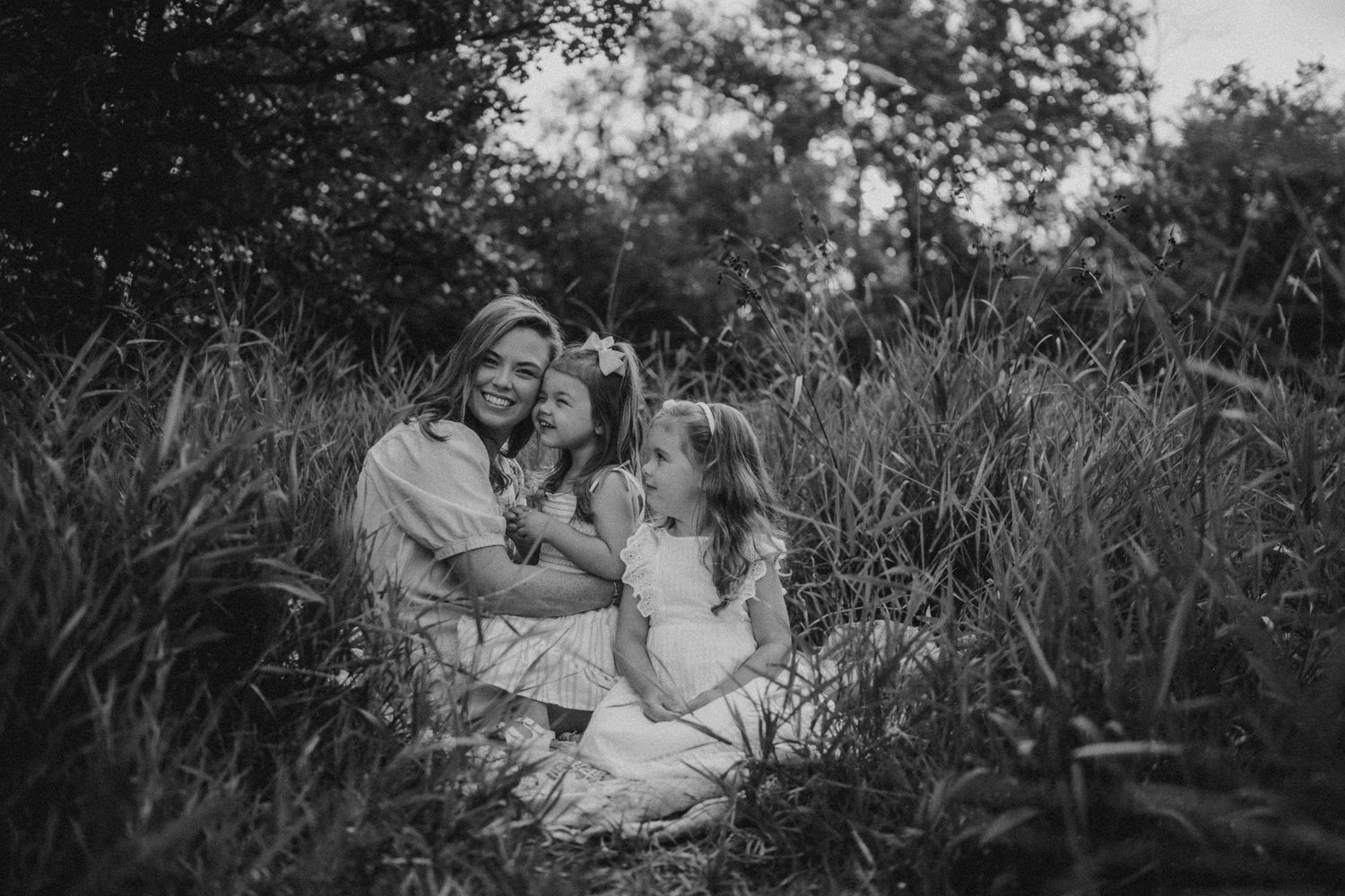 A black and white portrait of a family enjoying tender moments in nature.