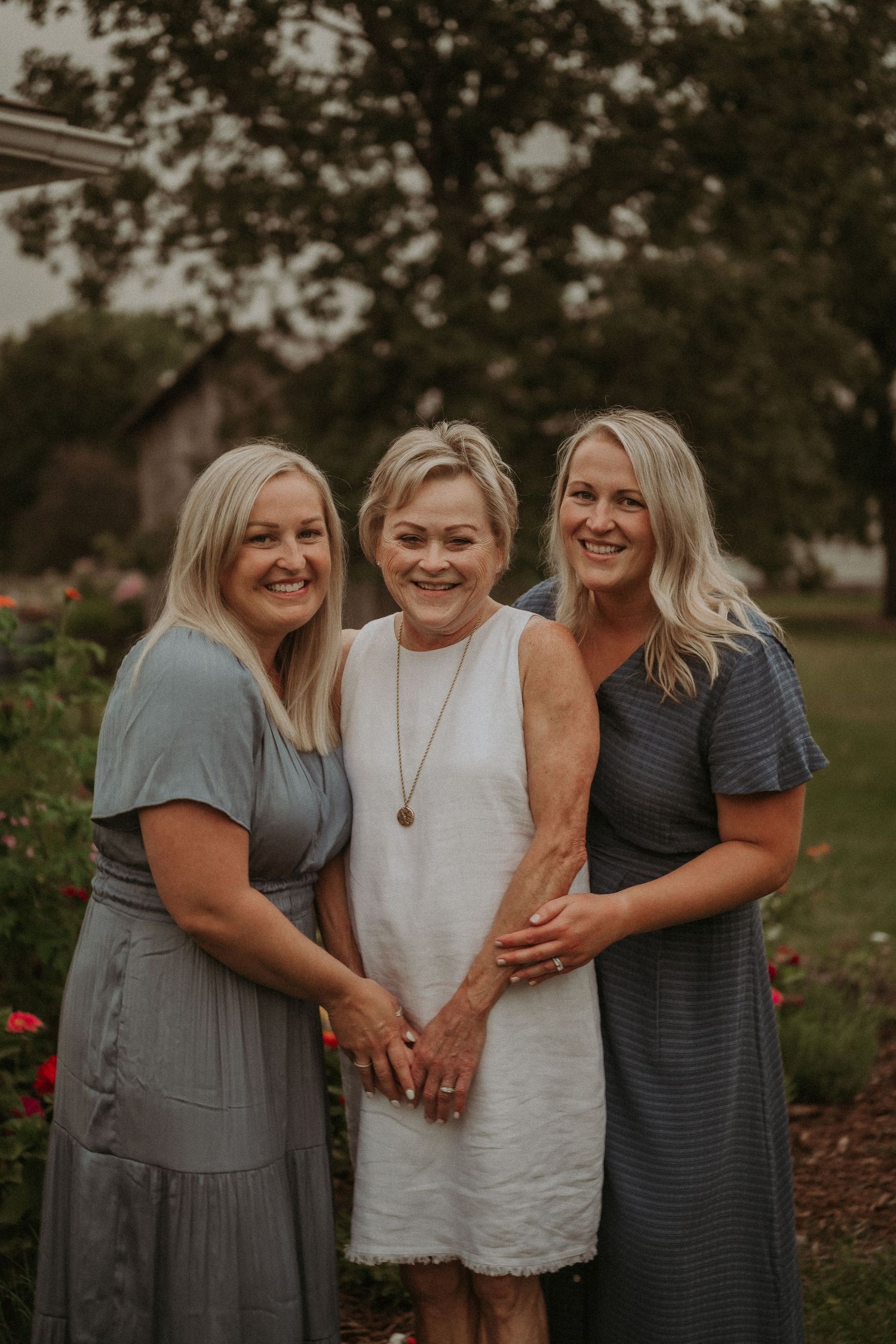 Three women share a laugh together in garden setting during golden hour.
