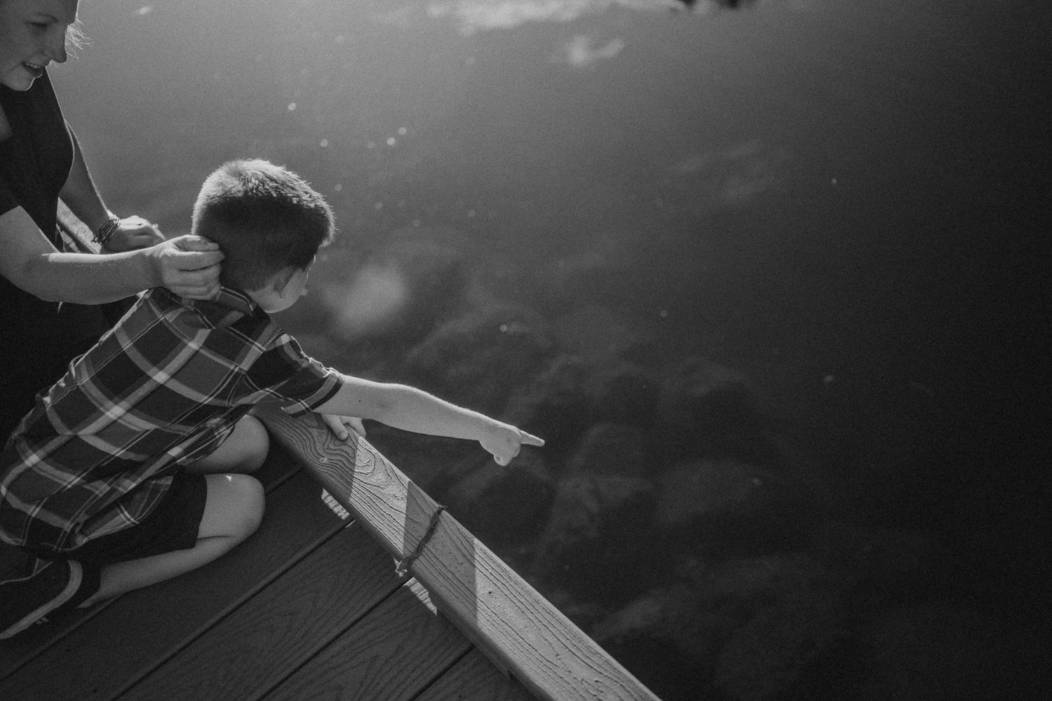 Black and white image of a fun moment on a dock overlooking water.