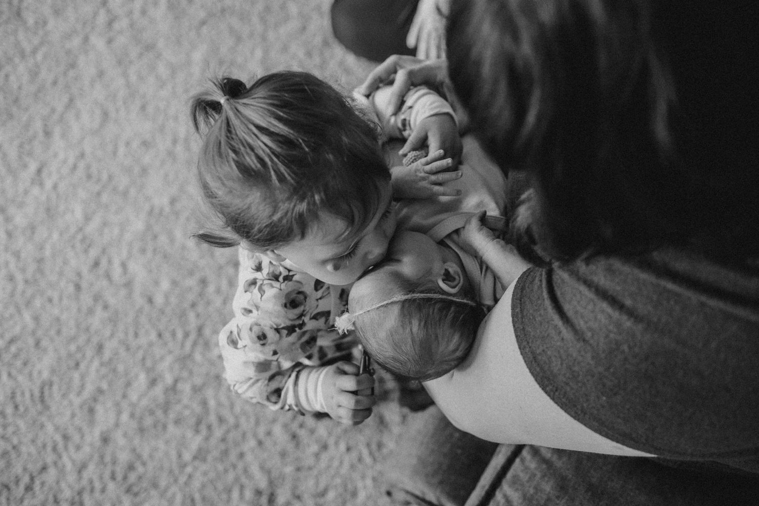 Black and white image of family members cradling and interacting with newborn.