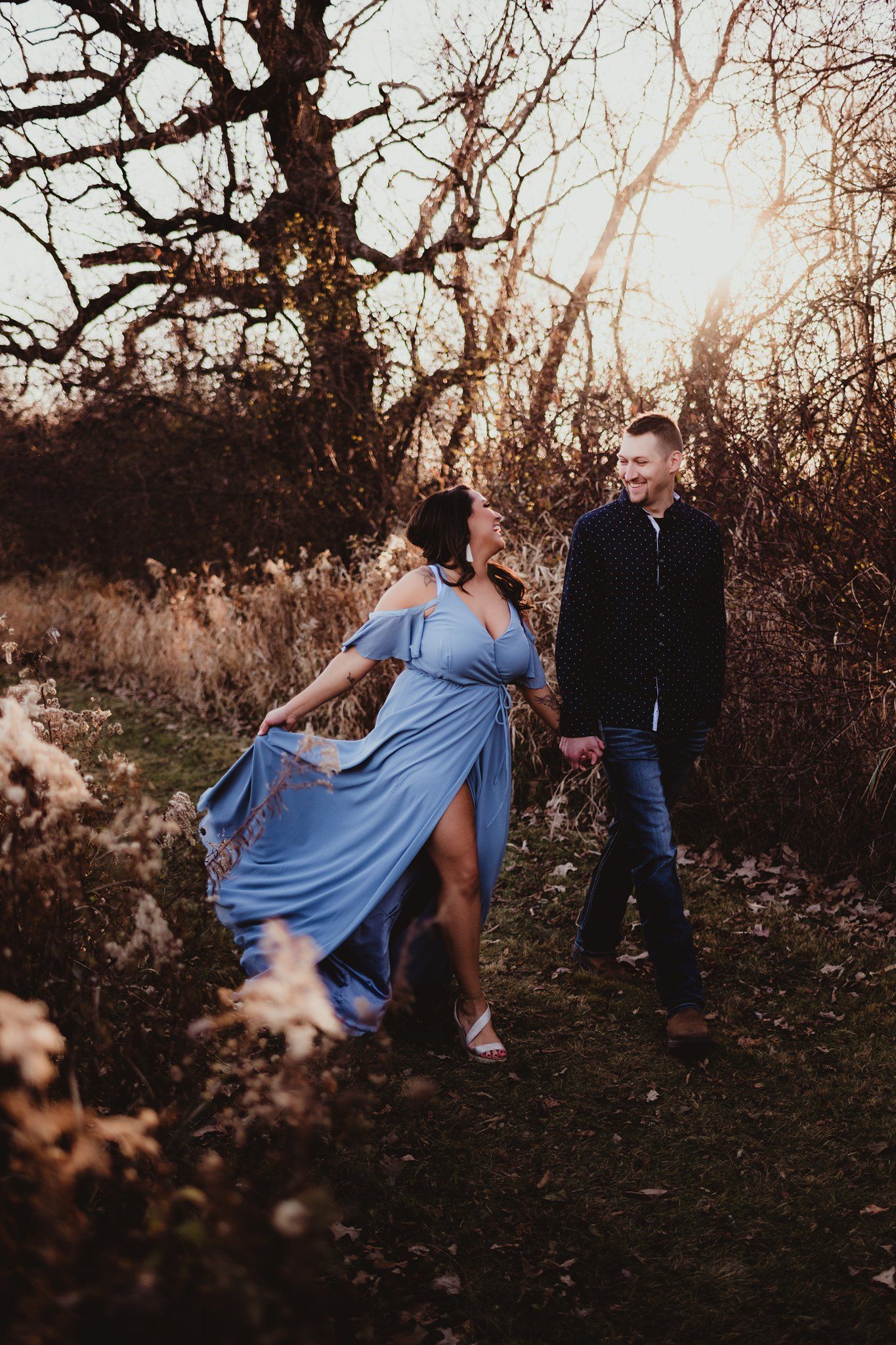 A couple in a field at sunset with flowing blue dress spinning in the evening light.