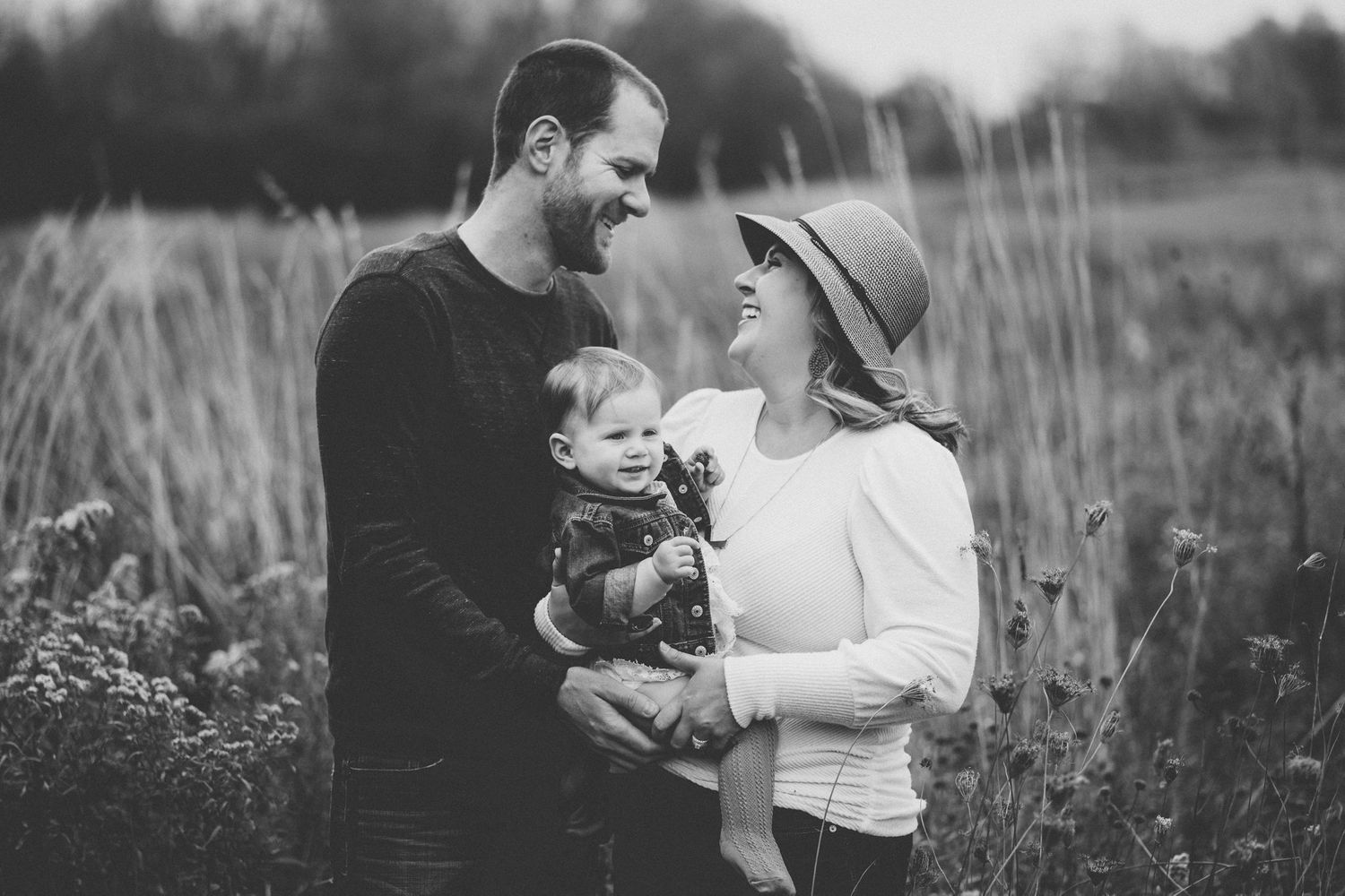 Black and white portrait of a family sharing an intimate moment in a field.