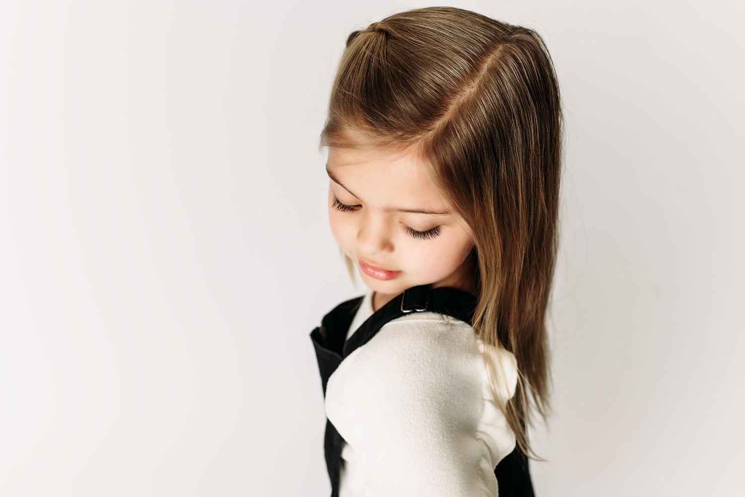 Side profile portrait showing downward gaze in black and white outfit.