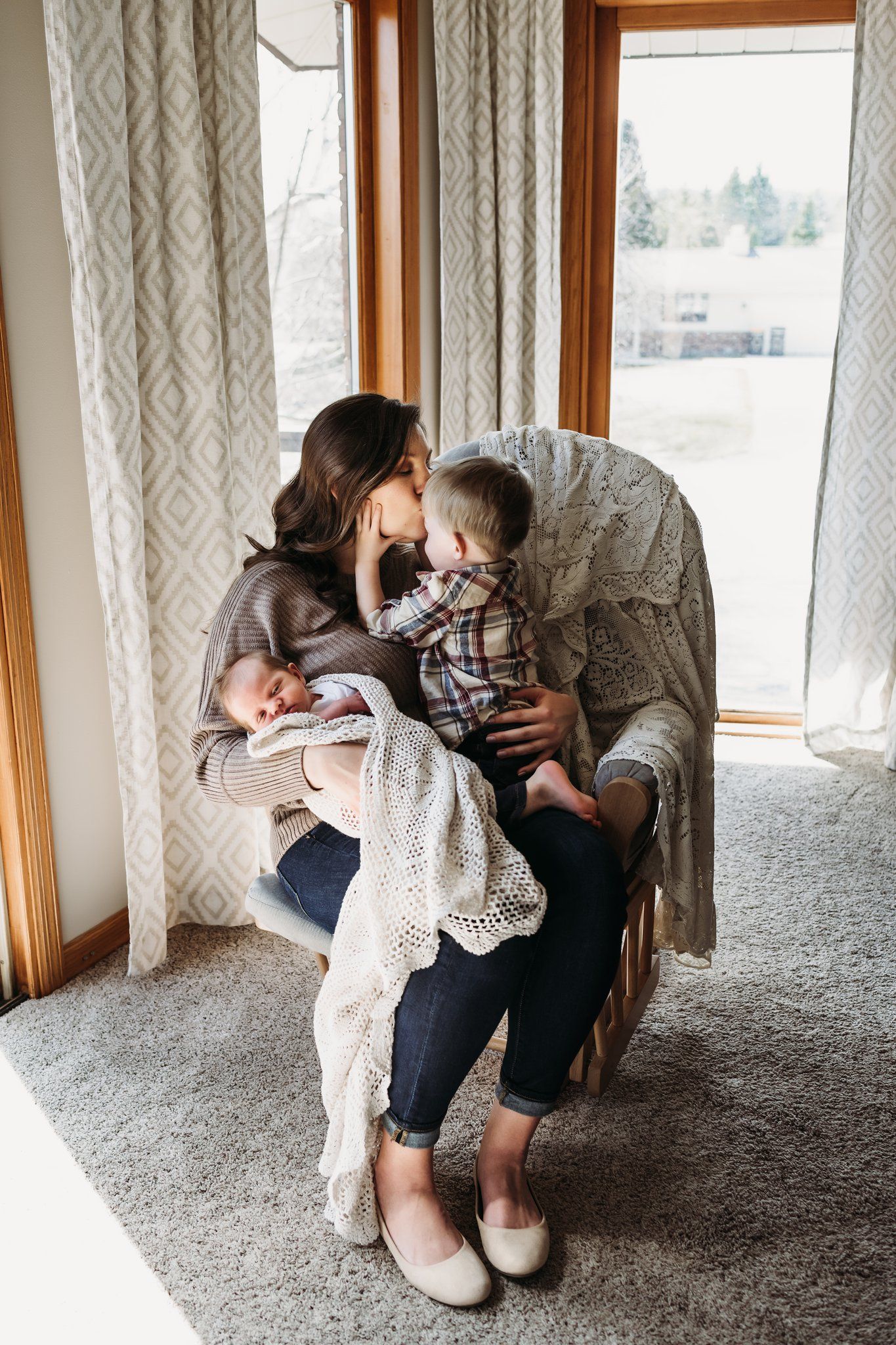 Intimate family portrait by window with soft natural lighting and cozy decor.
