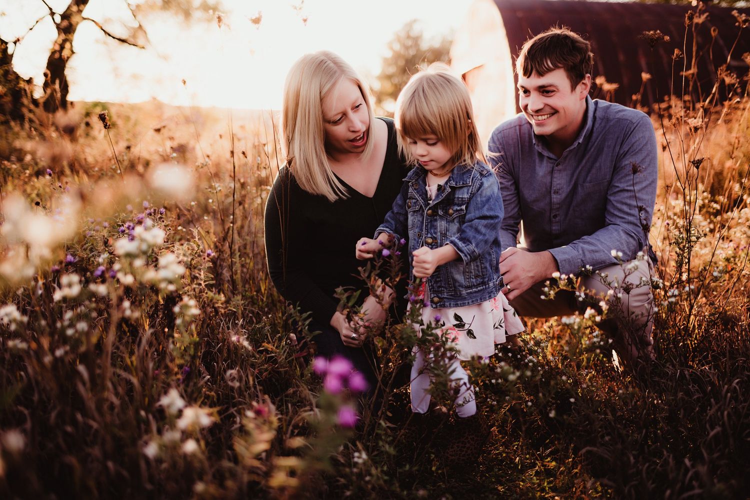 Family enjoying intimate moment together in field during sunset.
