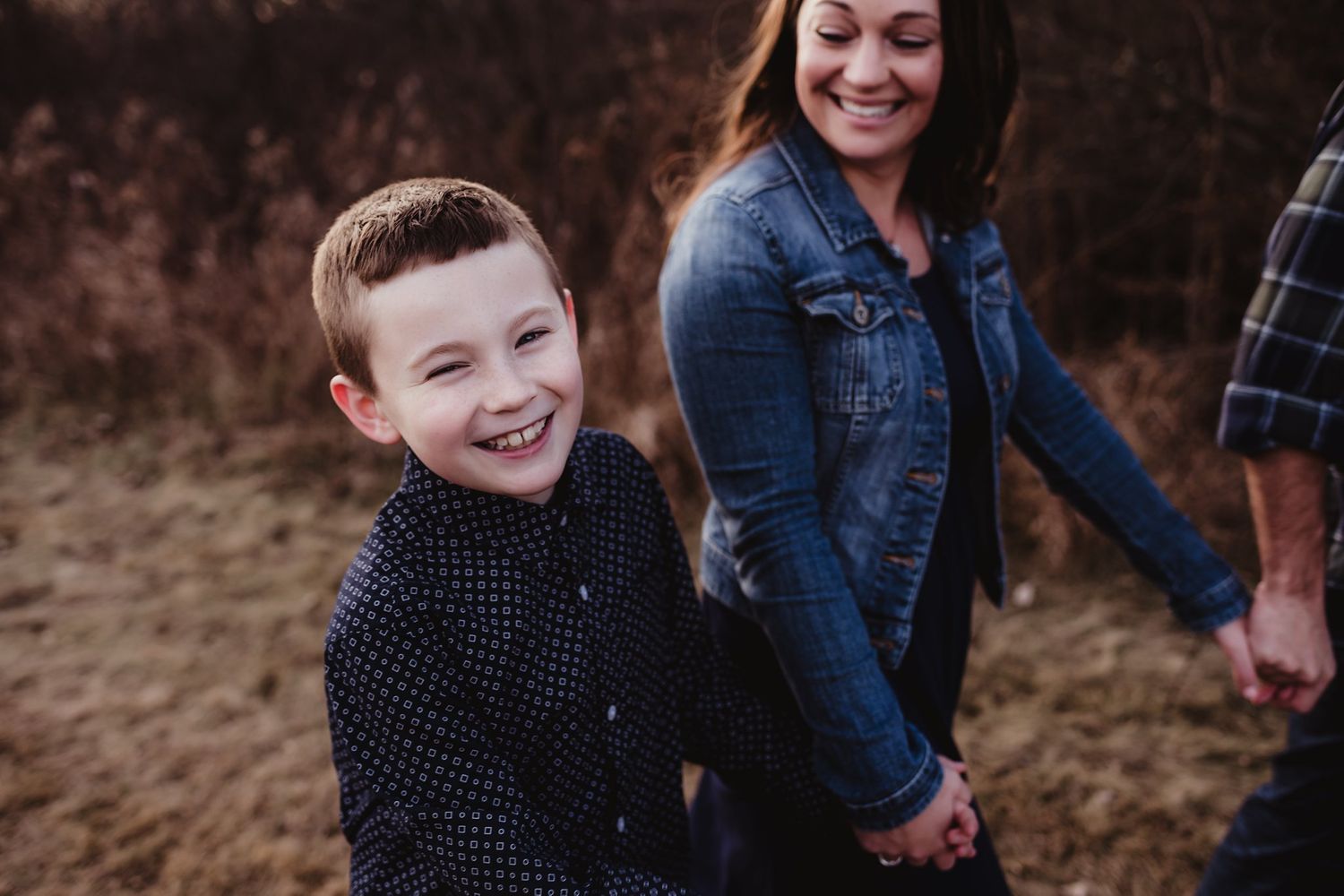 Family outdoors sharing joyful moments against rustic autumn backdrop.